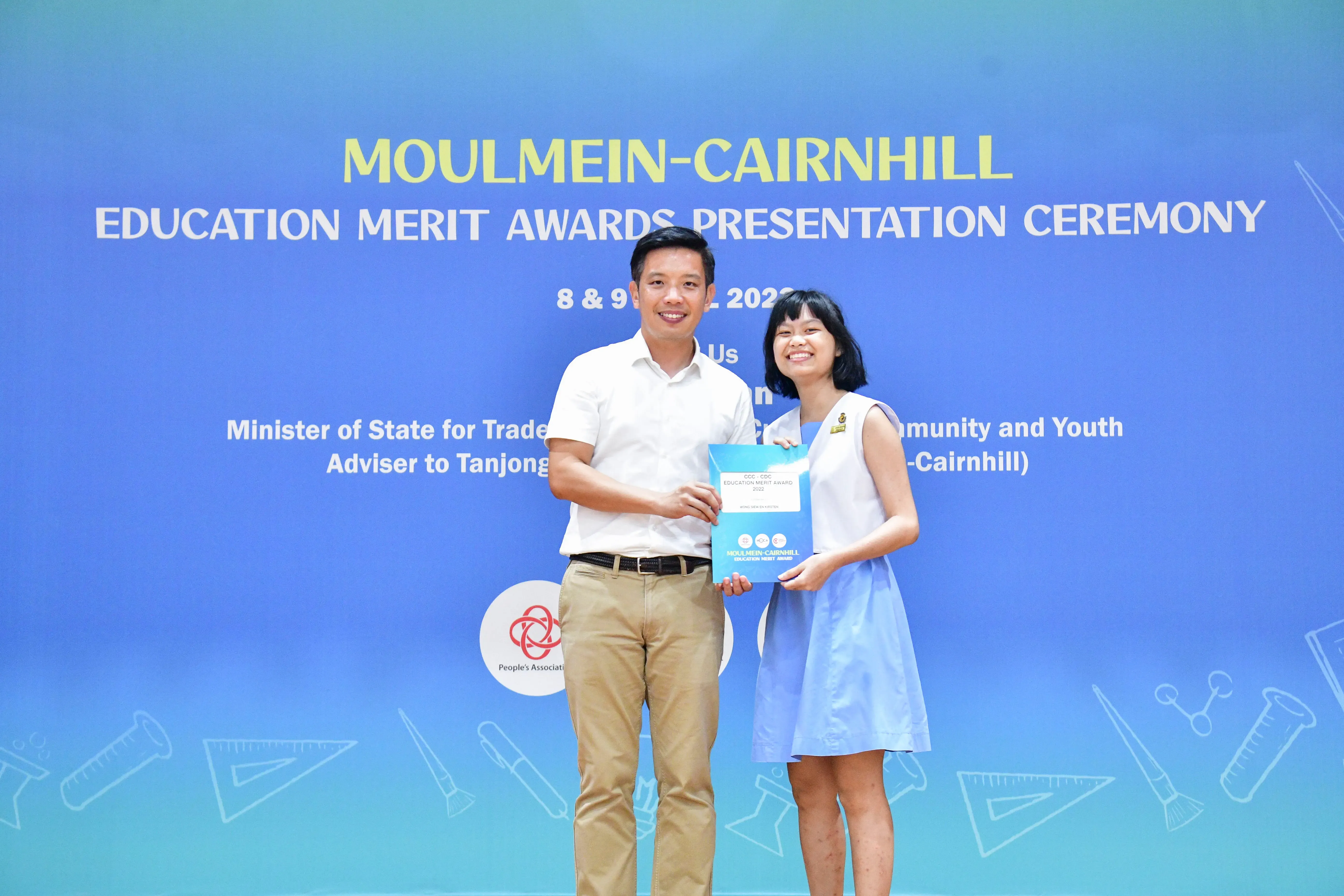 Two people smile holding a certificate at the Moulmein-Cairnhill Education Merit Awards Presentation Ceremony.
