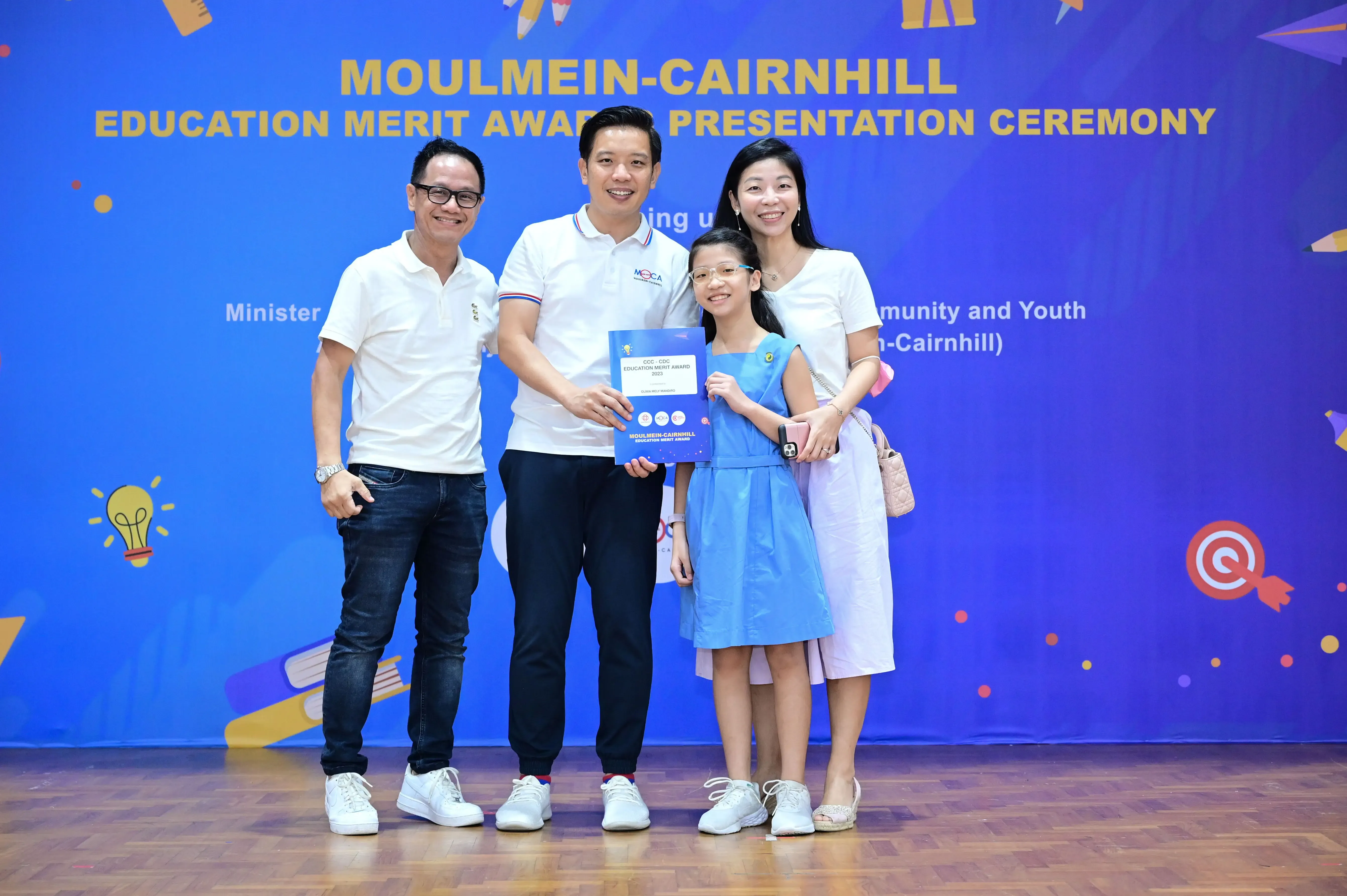 Three adults and a girl holding a certificate pose at the Moulmein-Cairnhill Education Merit Award Presentation Ceremony.