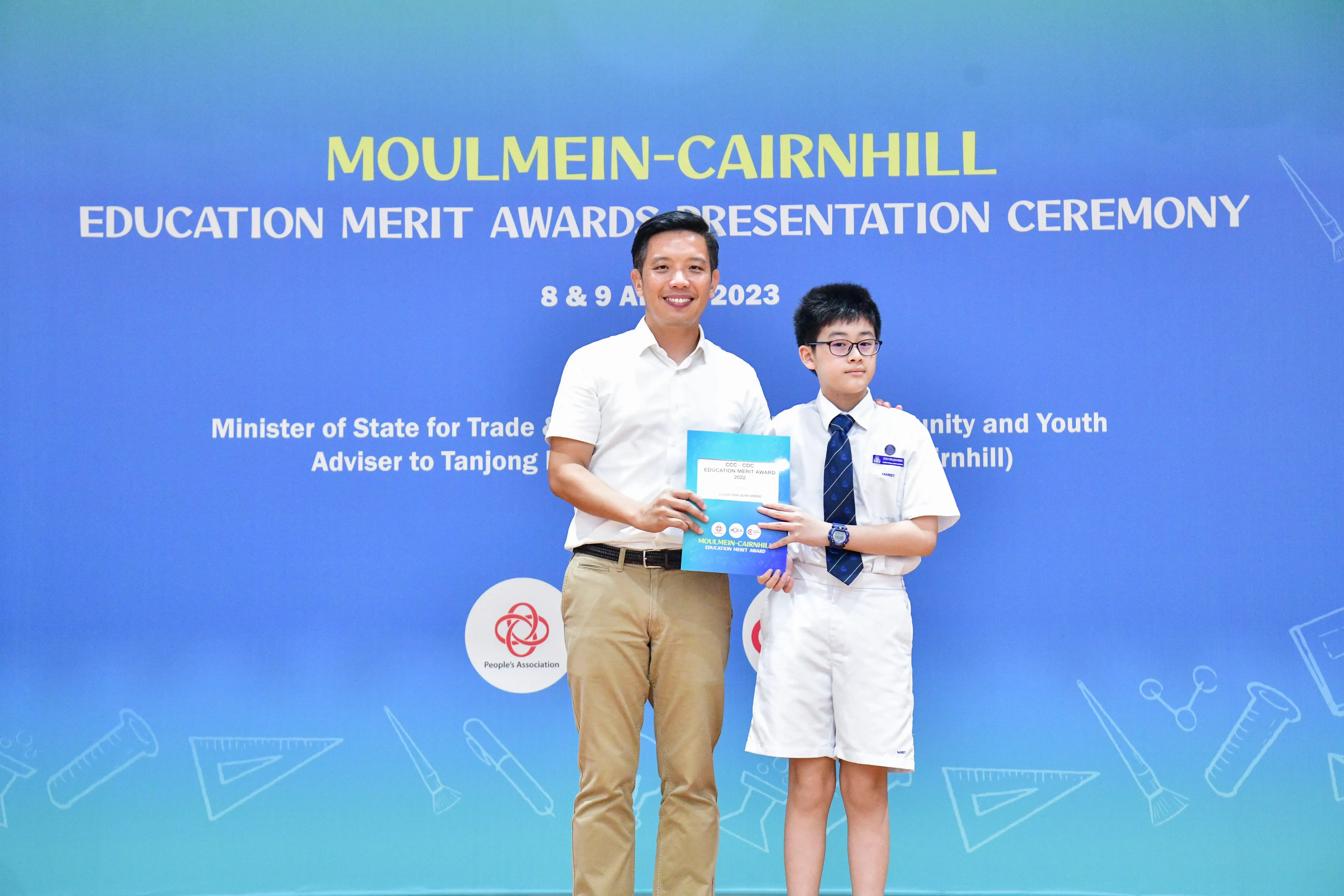 An adult and a uniformed student holding an award certificate at the Moulmein-Cairnhill Education Merit Awards 2023.
