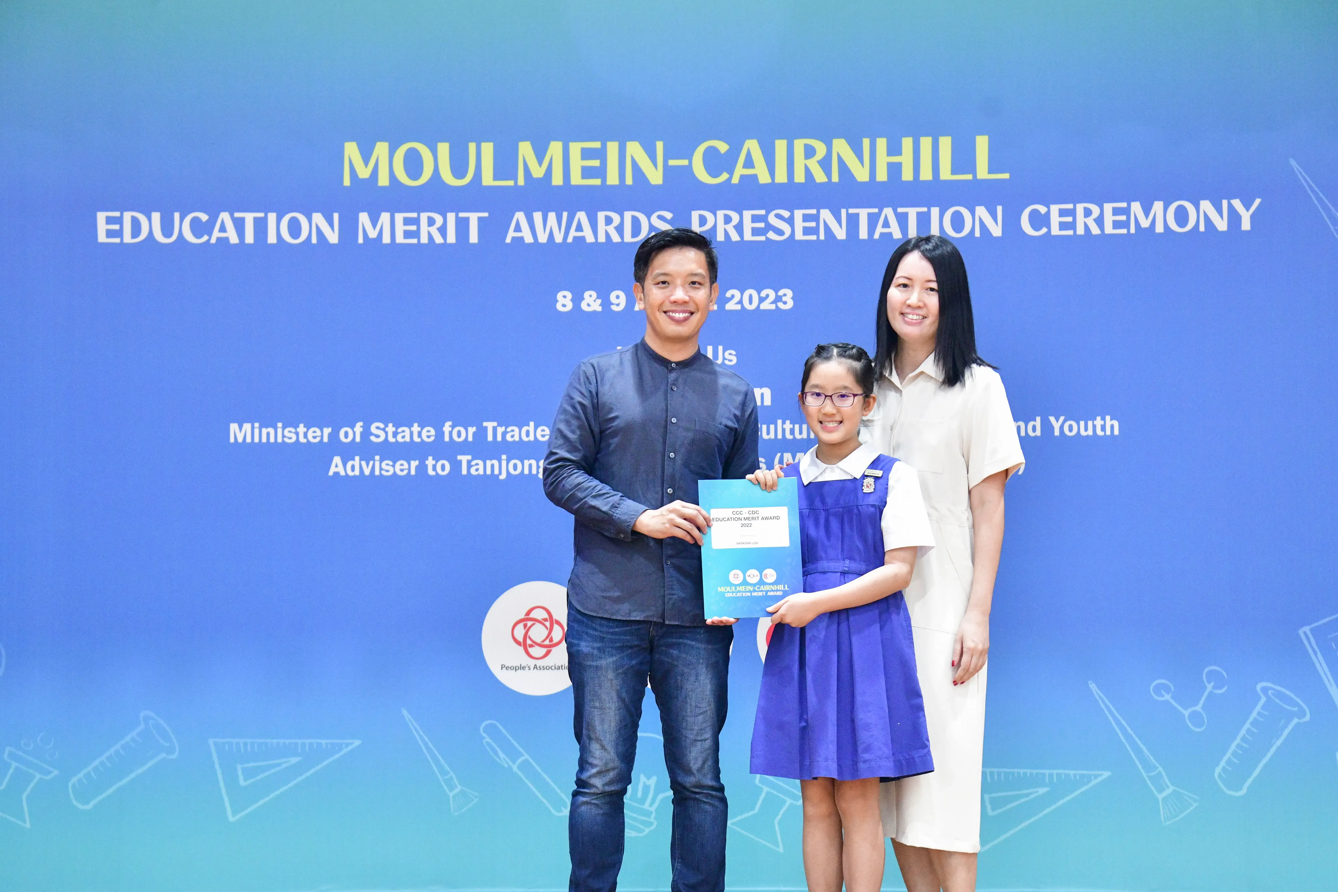 A man and woman pose with a young girl holding an award at the Moulmein-Cairnhill Education Merit Awards 2023.