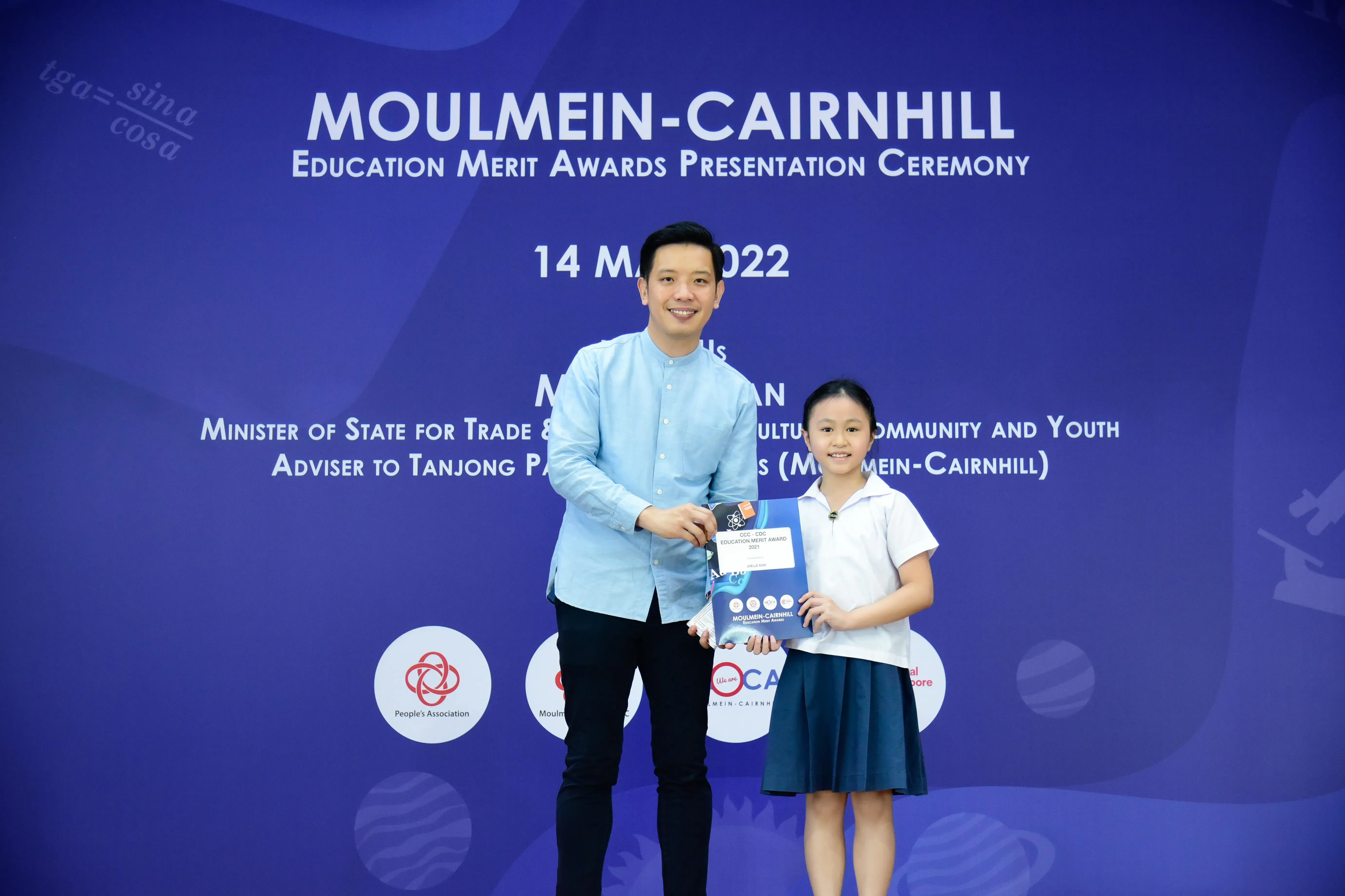 A man and a young girl hold an award certificate at the Moulmein-Cairnhill Education Merit Awards Ceremony, 14 May 2022.