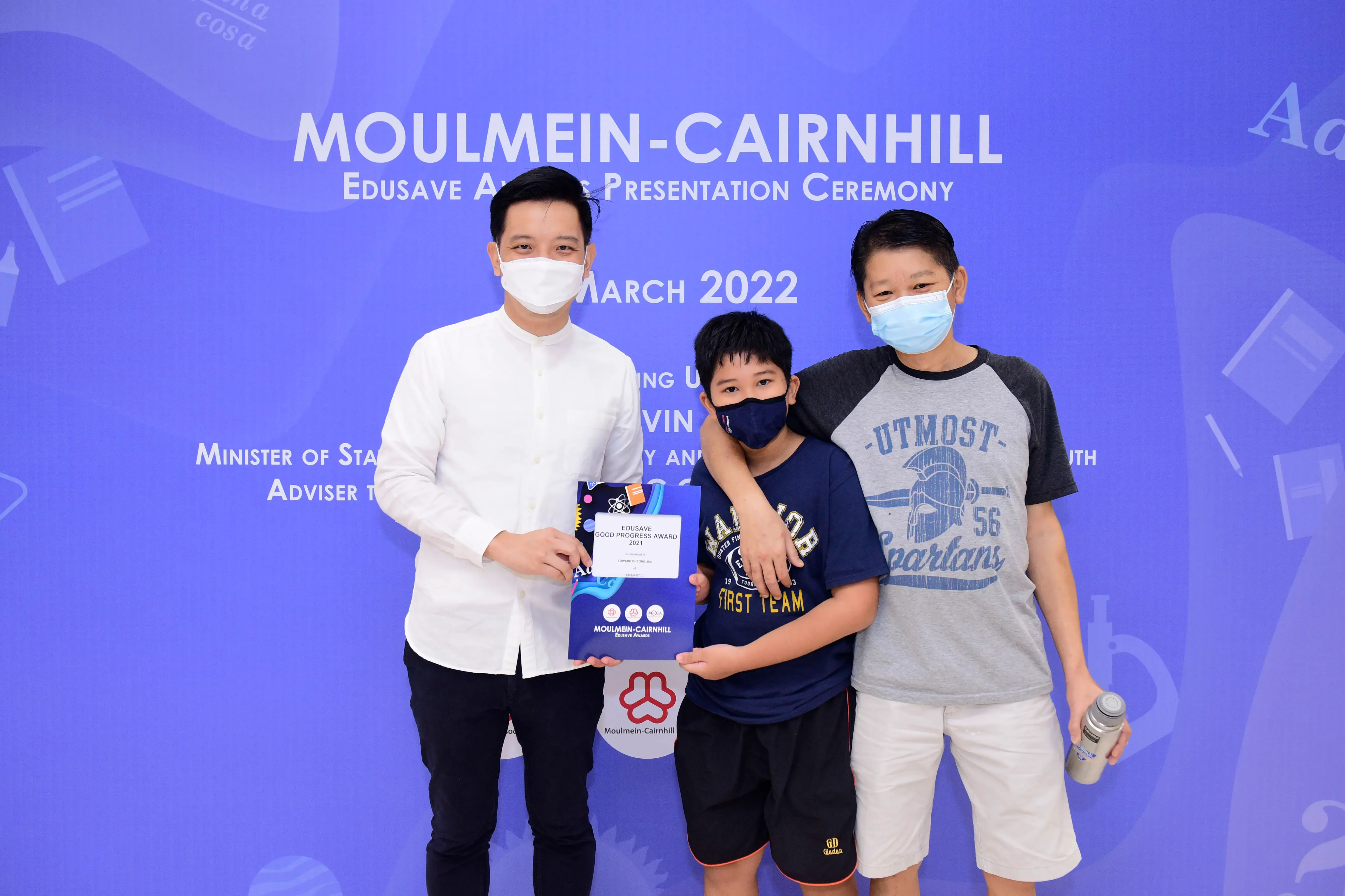 Three masked people pose at the Moulmein-Cairnhill Edusave Awards Presentation Ceremony in March 2022.
