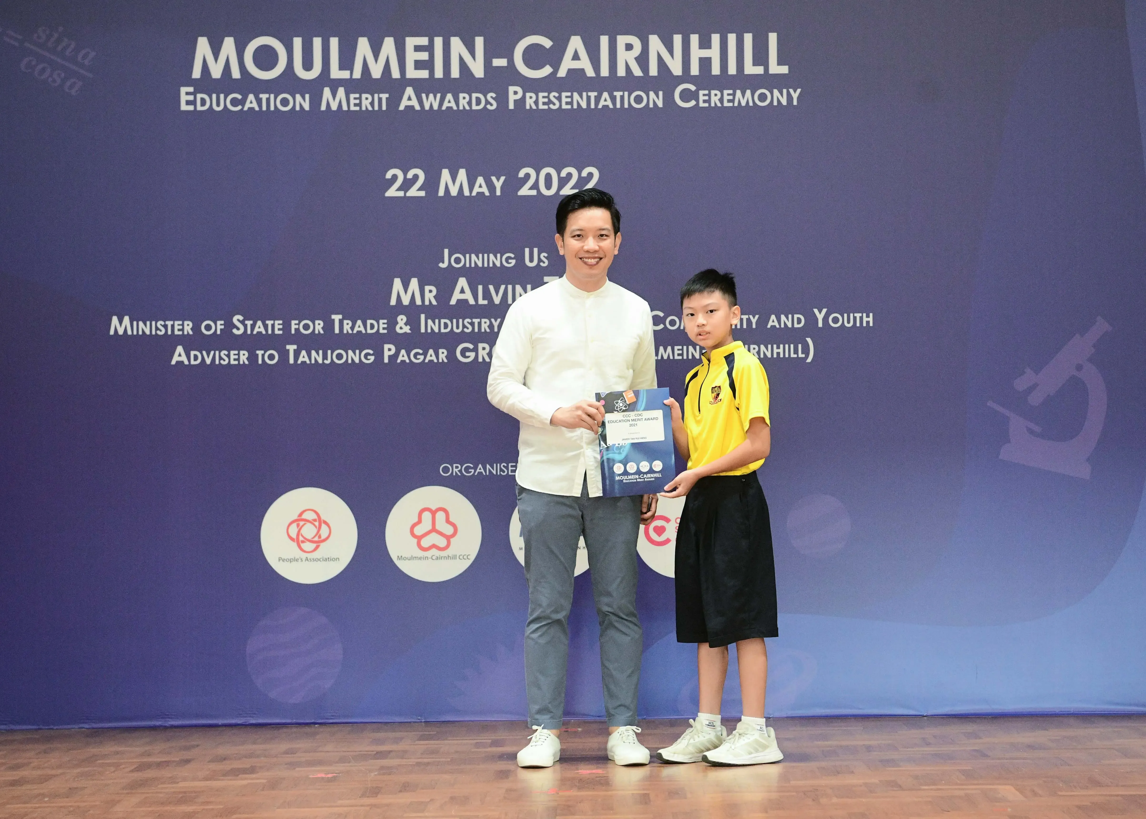 A man and a young boy hold an award at the Moulmein-Cairnhill Education Merit Awards Ceremony on 22 May 2022.