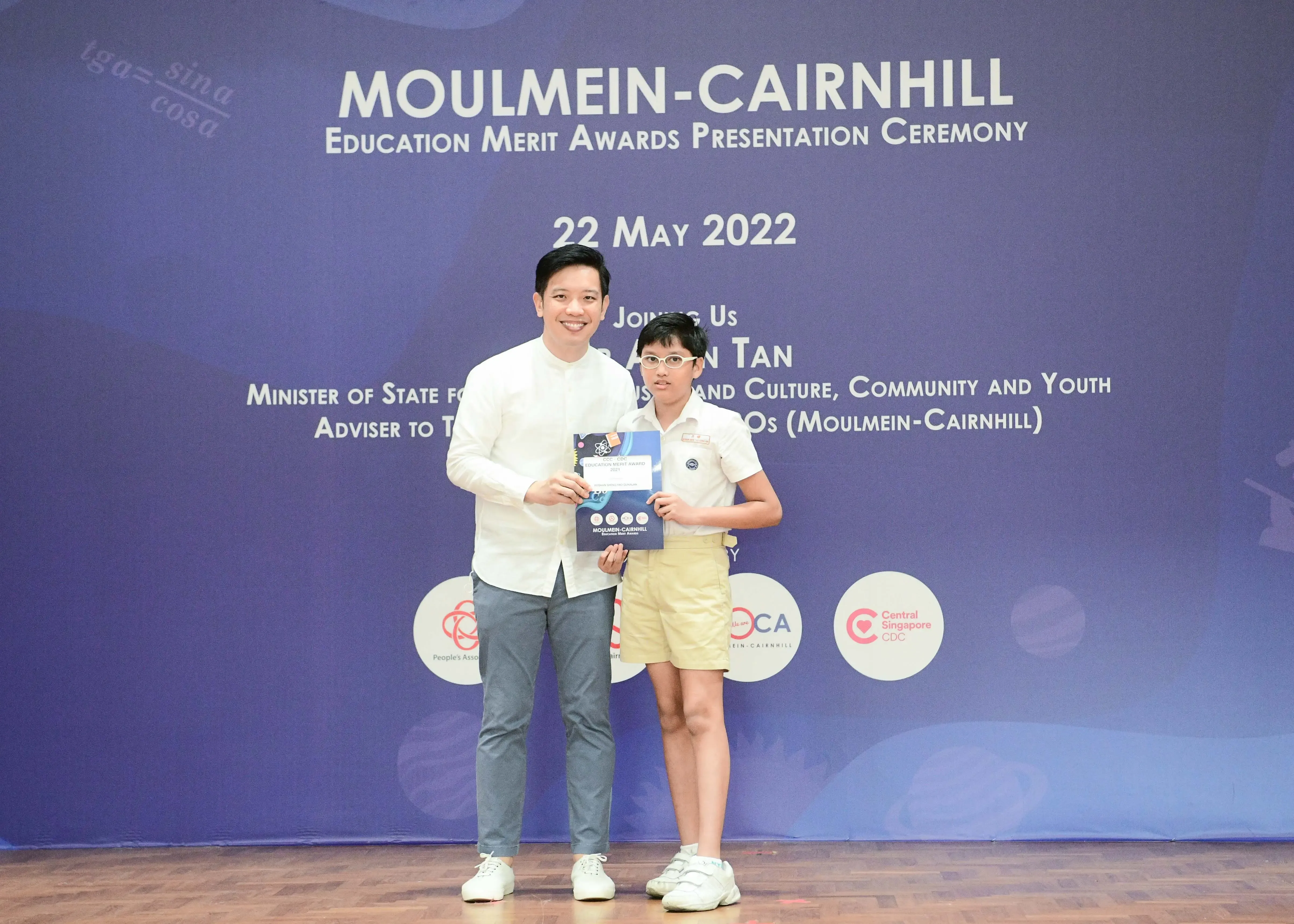 An adult and a child hold an award booklet at the Moulmein-Cairnhill Education Merit Awards ceremony on 22 May 2022.