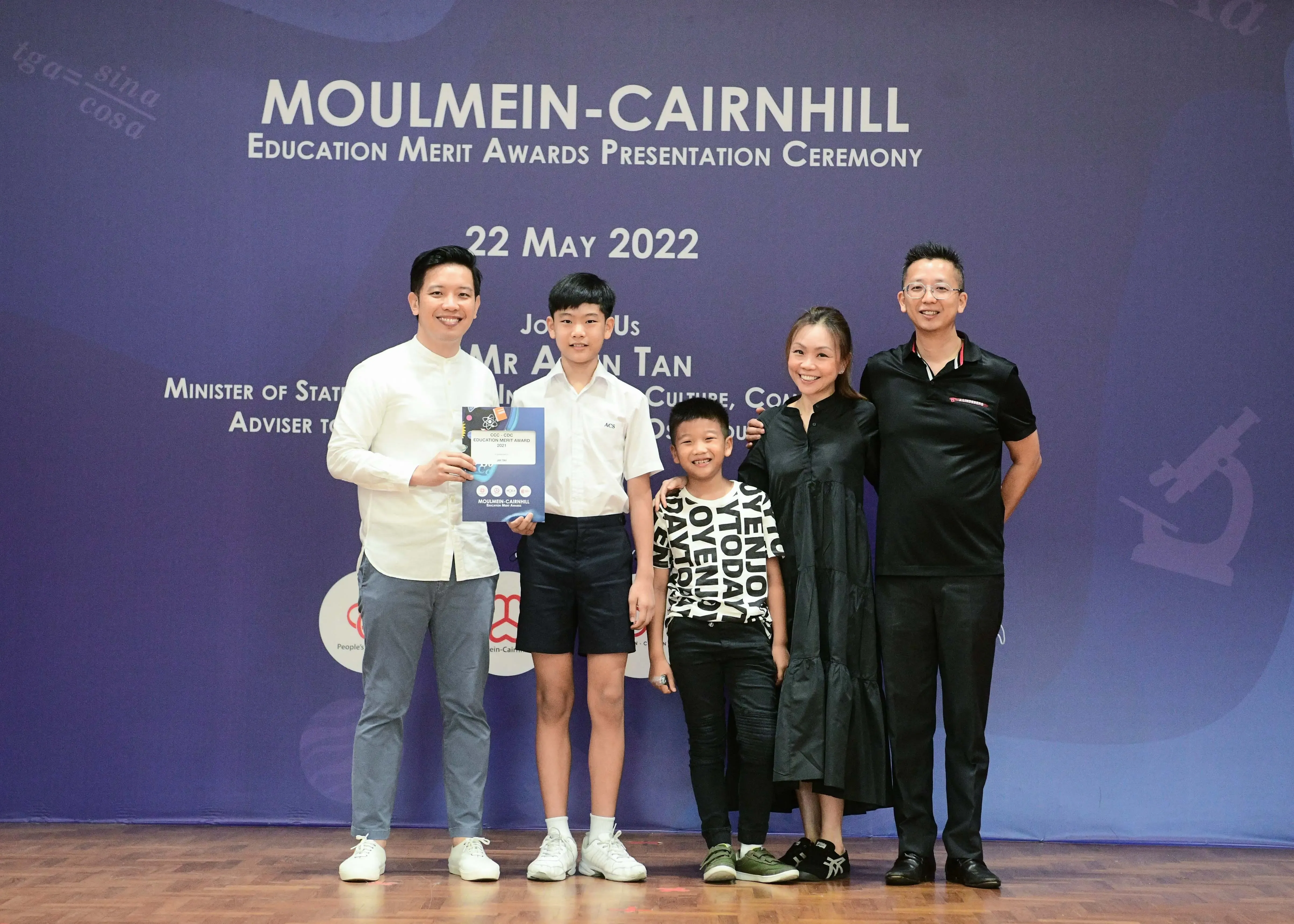 Five people pose on stage at the Moulmein-Cairnhill Education Merit Awards ceremony on 22 May 2022.