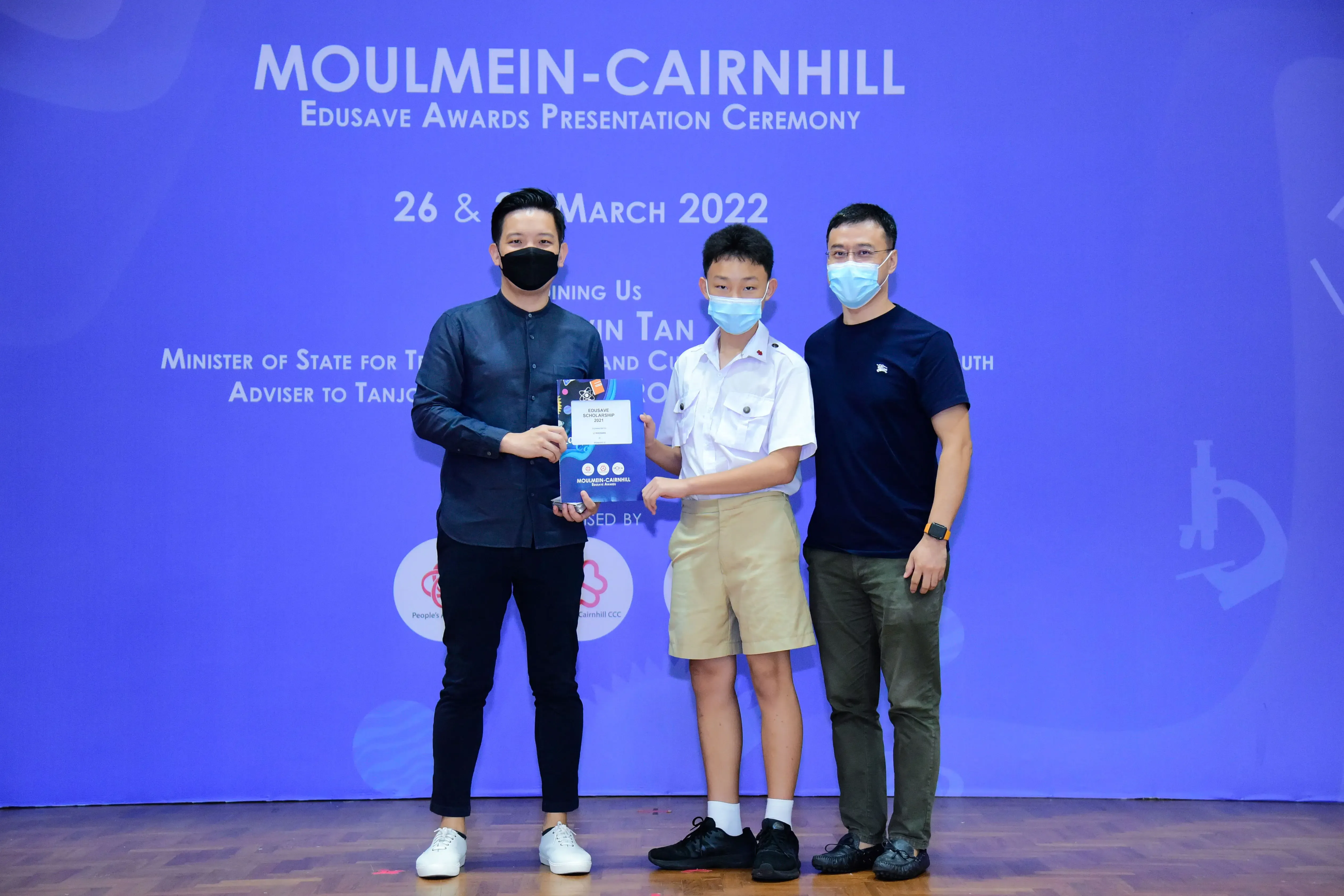 Three masked people pose at the Moulmein-Cairnhill Edusave Awards Presentation Ceremony in March 2022.