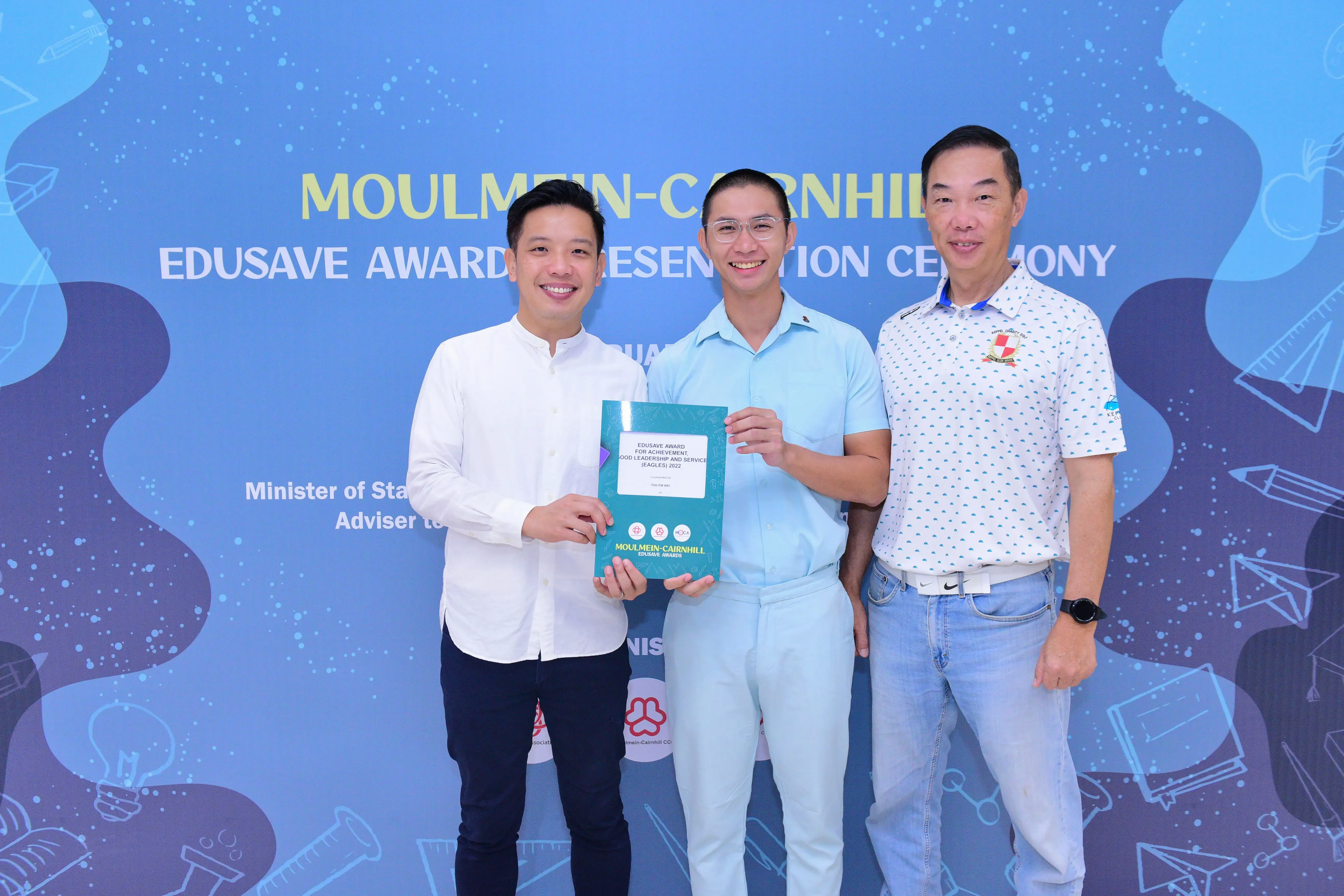 Three smiling men pose together holding an Edusave award certificate at the Moulmein-Cairnhill Edusave Awards Ceremony.