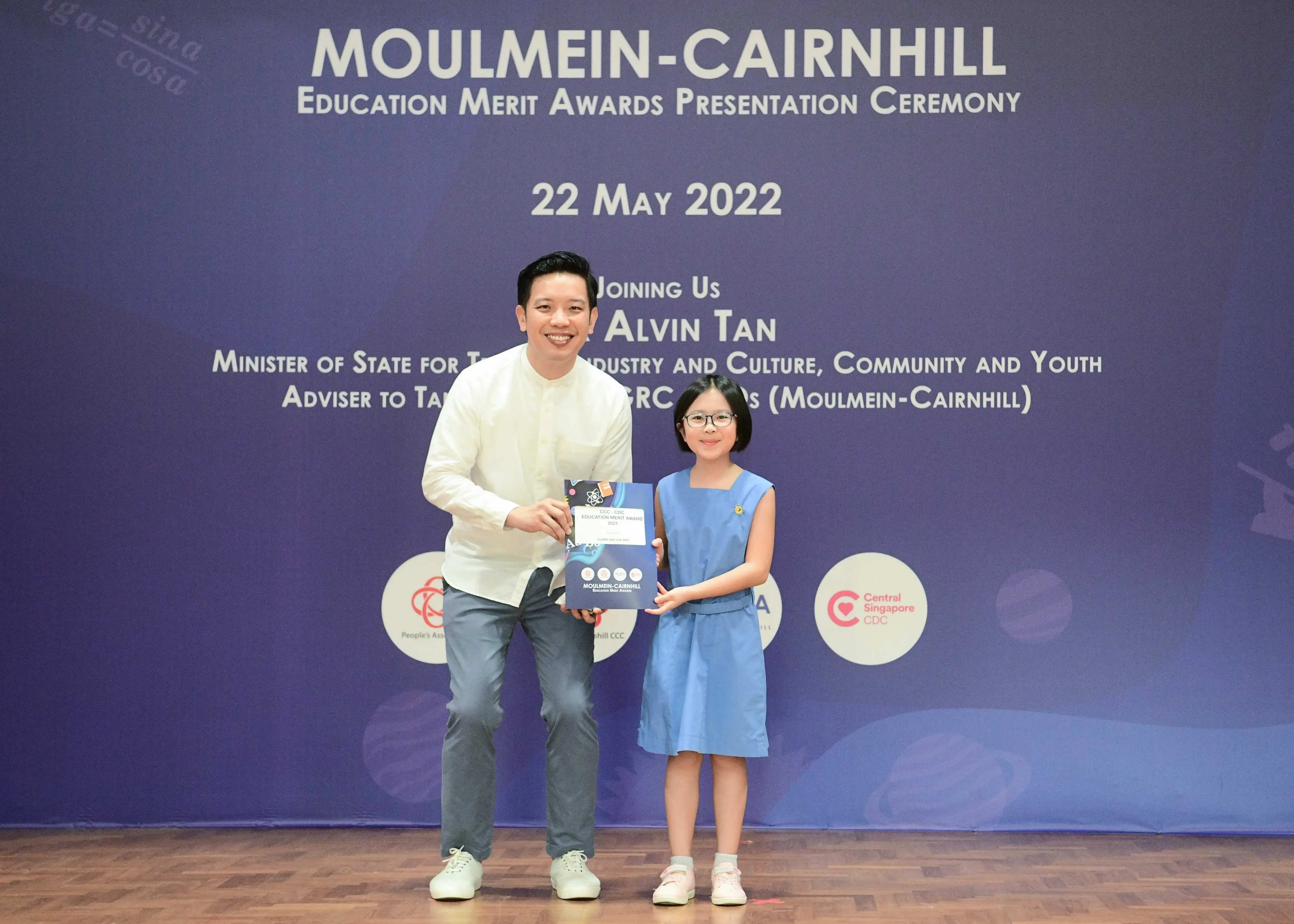 A man and a young girl hold an award booklet at the Moulmein-Cairnhill Education Merit Awards on 22 May 2022.