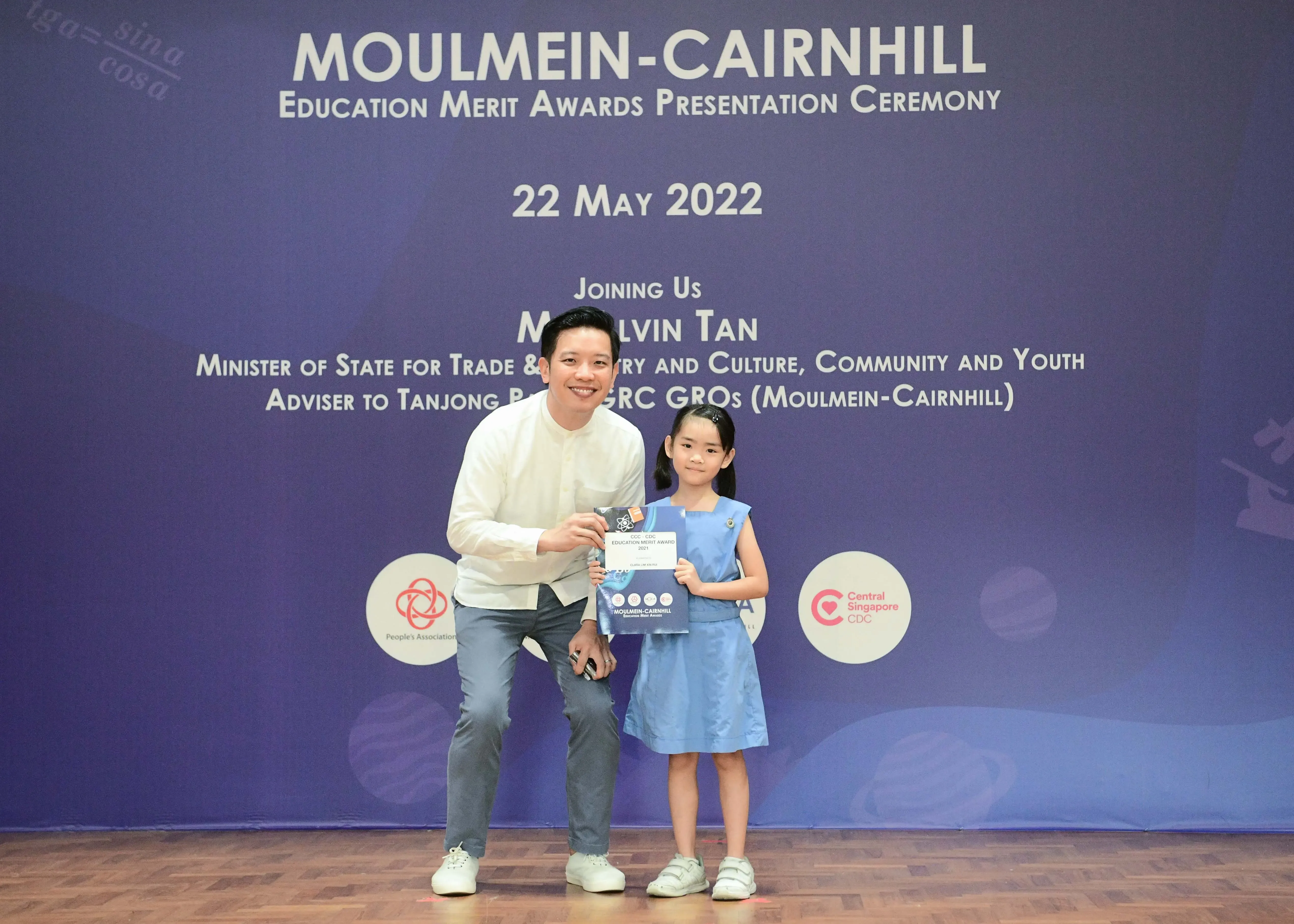 A man and a young girl hold an award together at the Moulmein-Cairnhill Education Merit Awards ceremony on 22 May 2022.