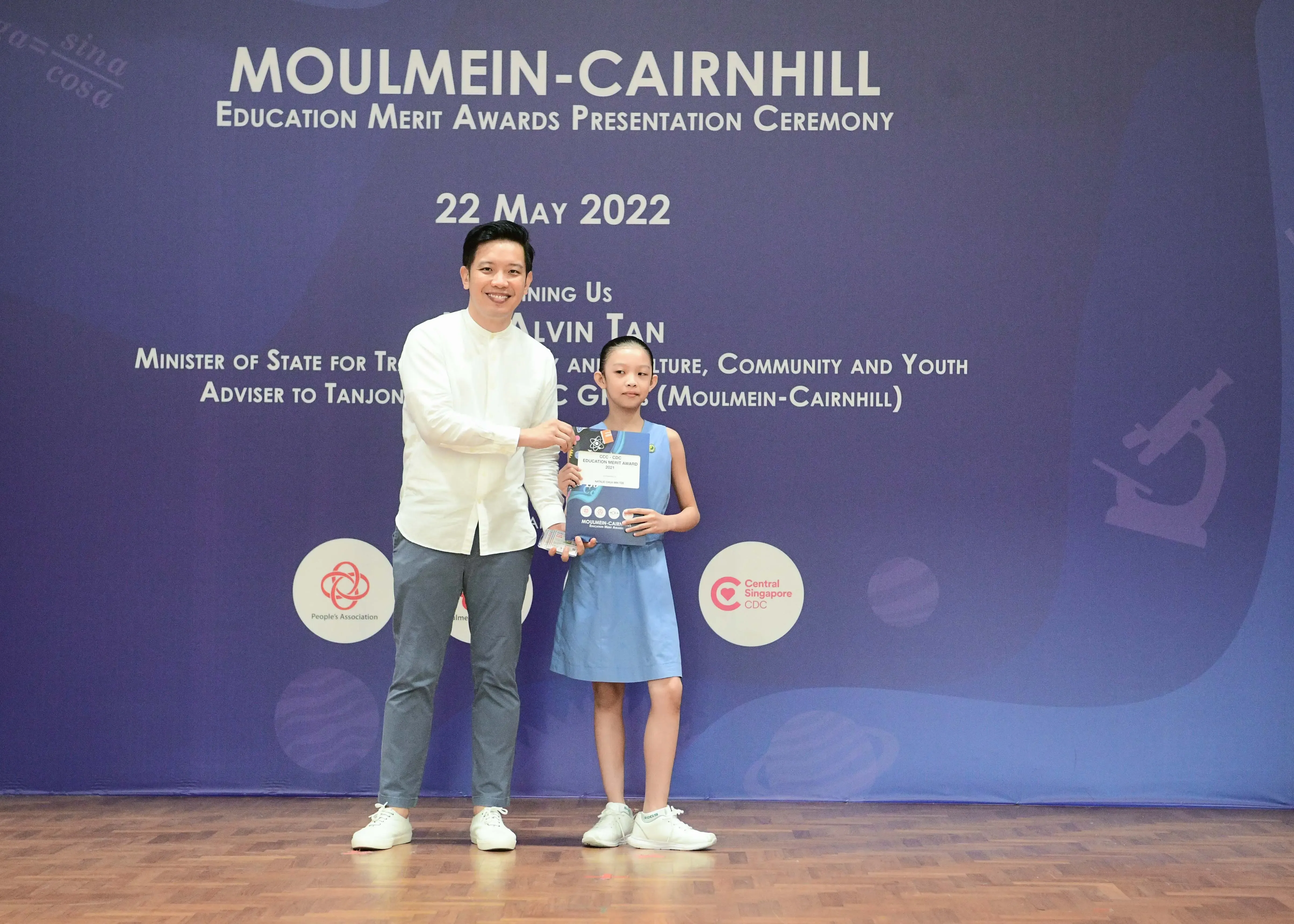 A man presents an award to a young girl at the Moulmein-Cairnhill Education Merit Awards Ceremony on 22 May 2022.