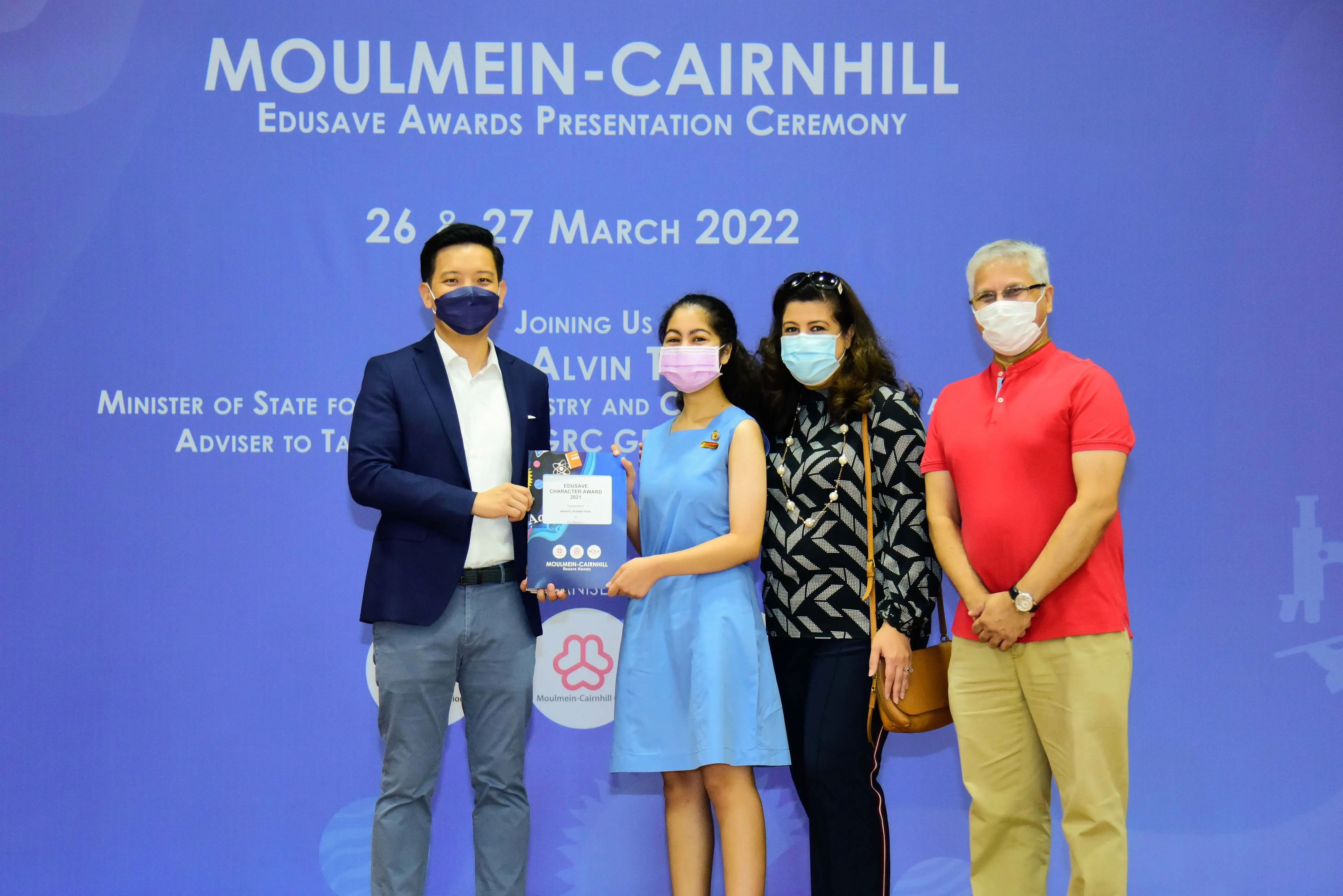 Four masked people pose at the Moulmein-Cairnhill Edusave Awards Presentation Ceremony on 26-27 March 2022.