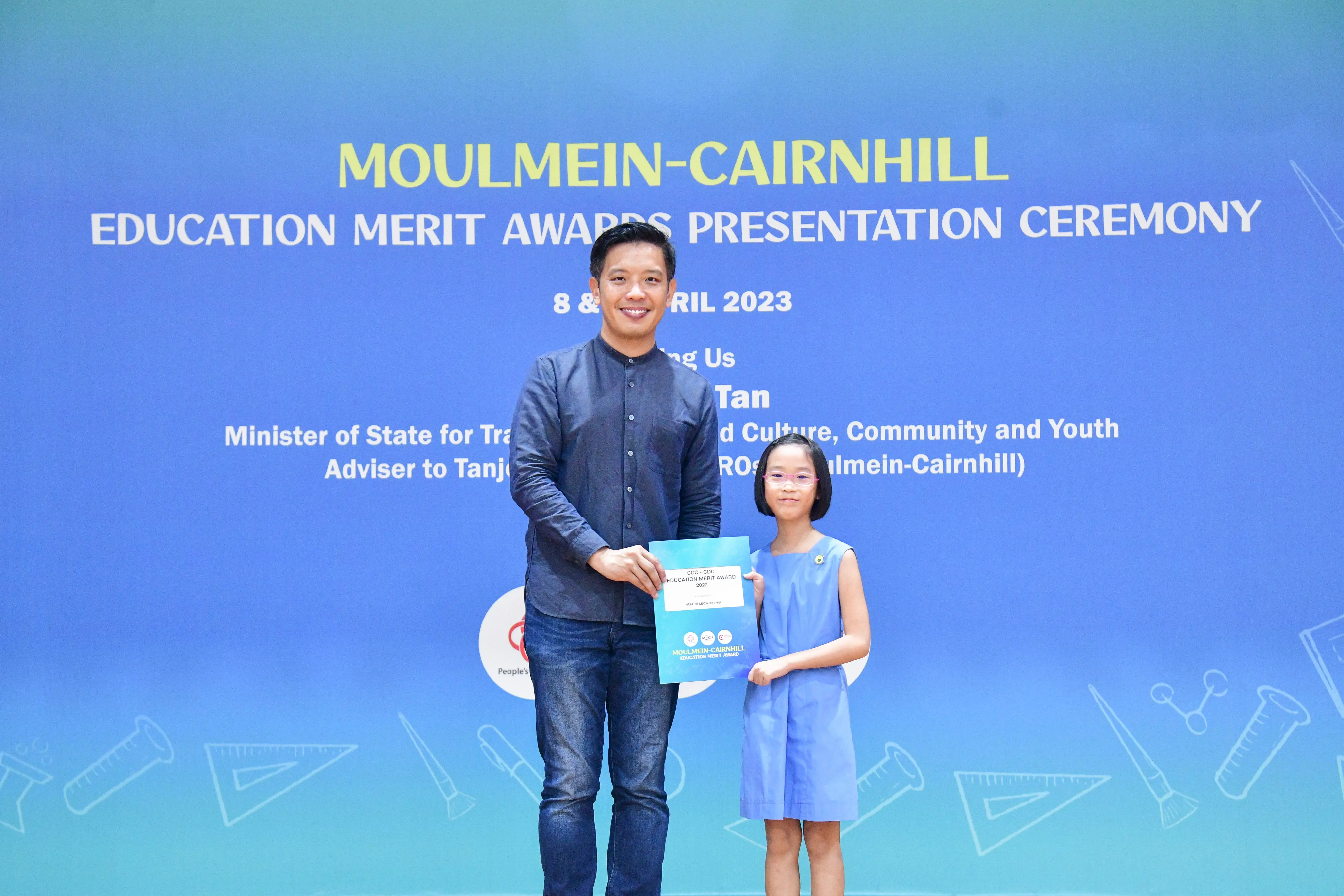 A man and a young girl hold an award certificate together at the Moulmein-Cairnhill Education Merit Awards Ceremony 2023.