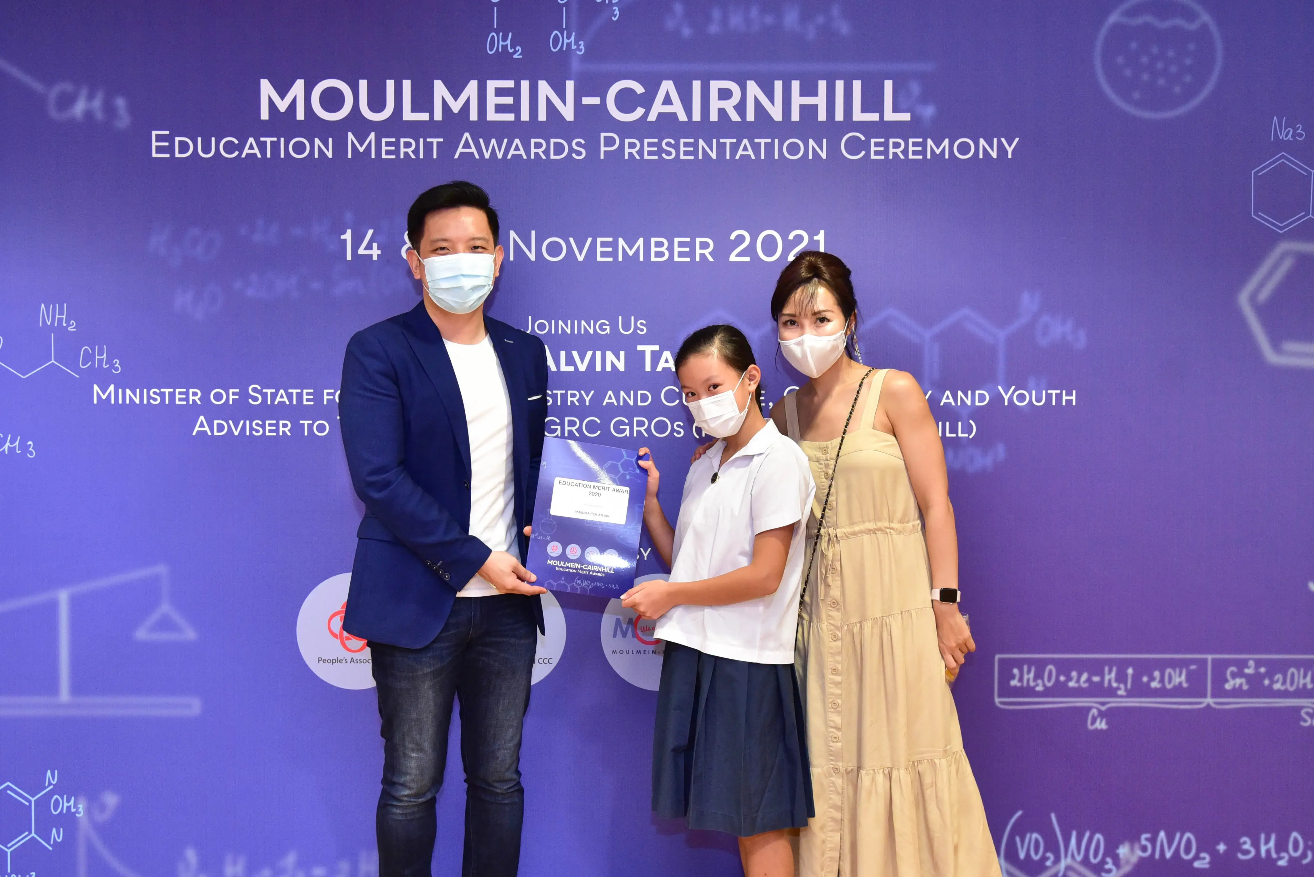 Three masked people pose with an award certificate at the Moulmein-Cairnhill Education Merit Awards Ceremony, November 2021.