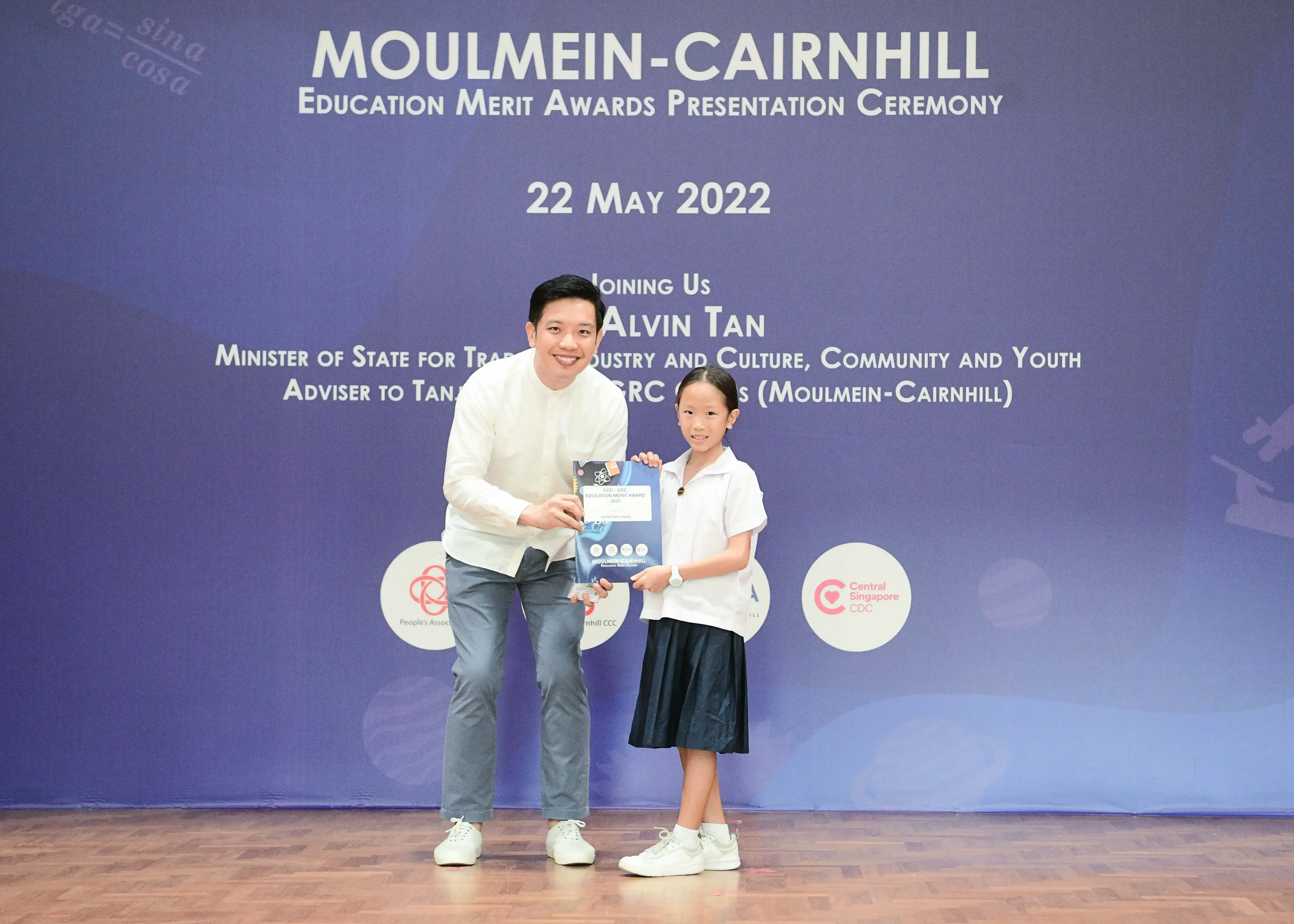 A man and a young girl hold a certificate at the Moulmein-Cairnhill Education Merit Awards on 22 May 2022.