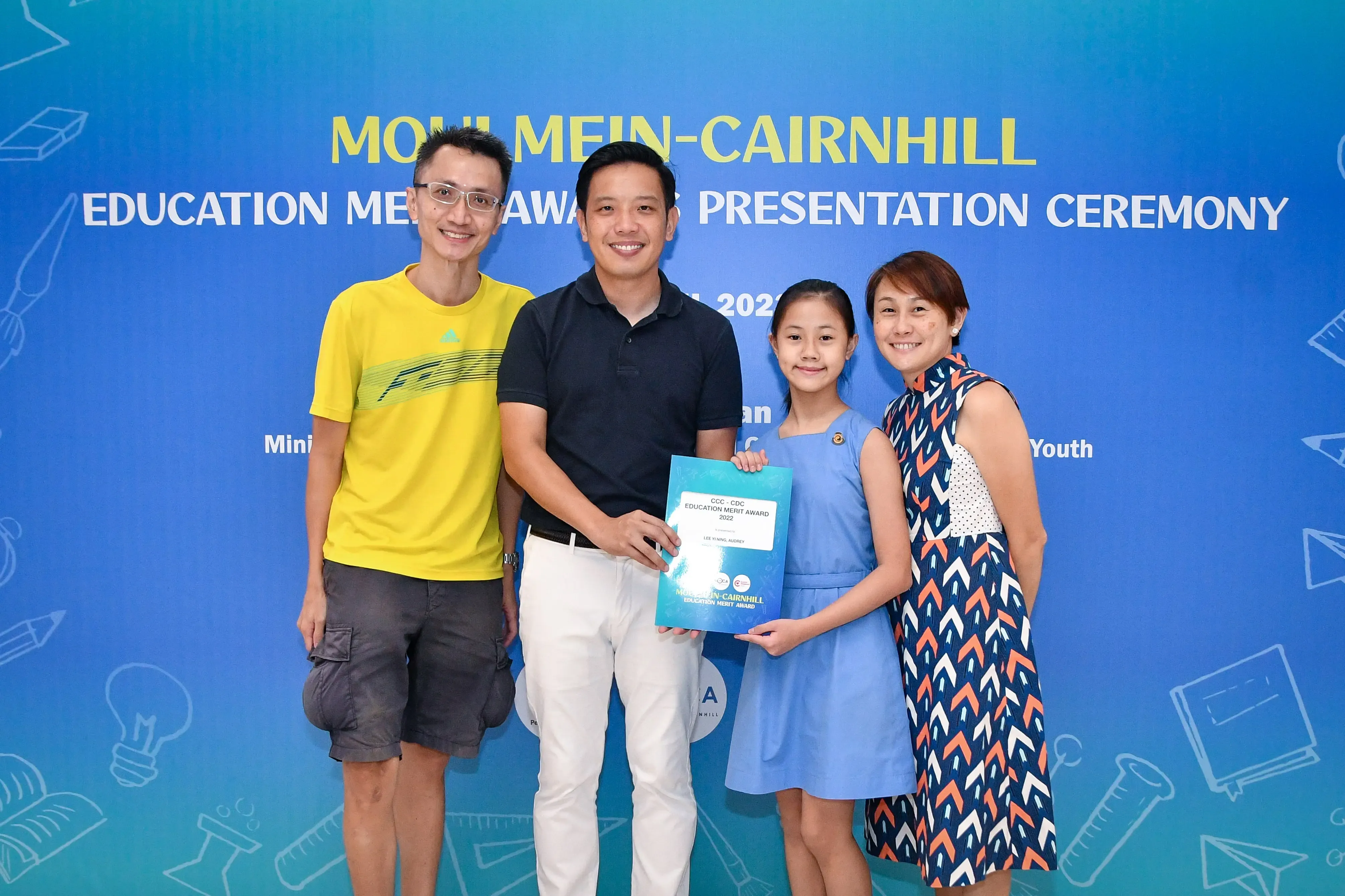 Four people pose with a certificate at the Moulmein-Cairnhill Education Merit Award Presentation Ceremony.