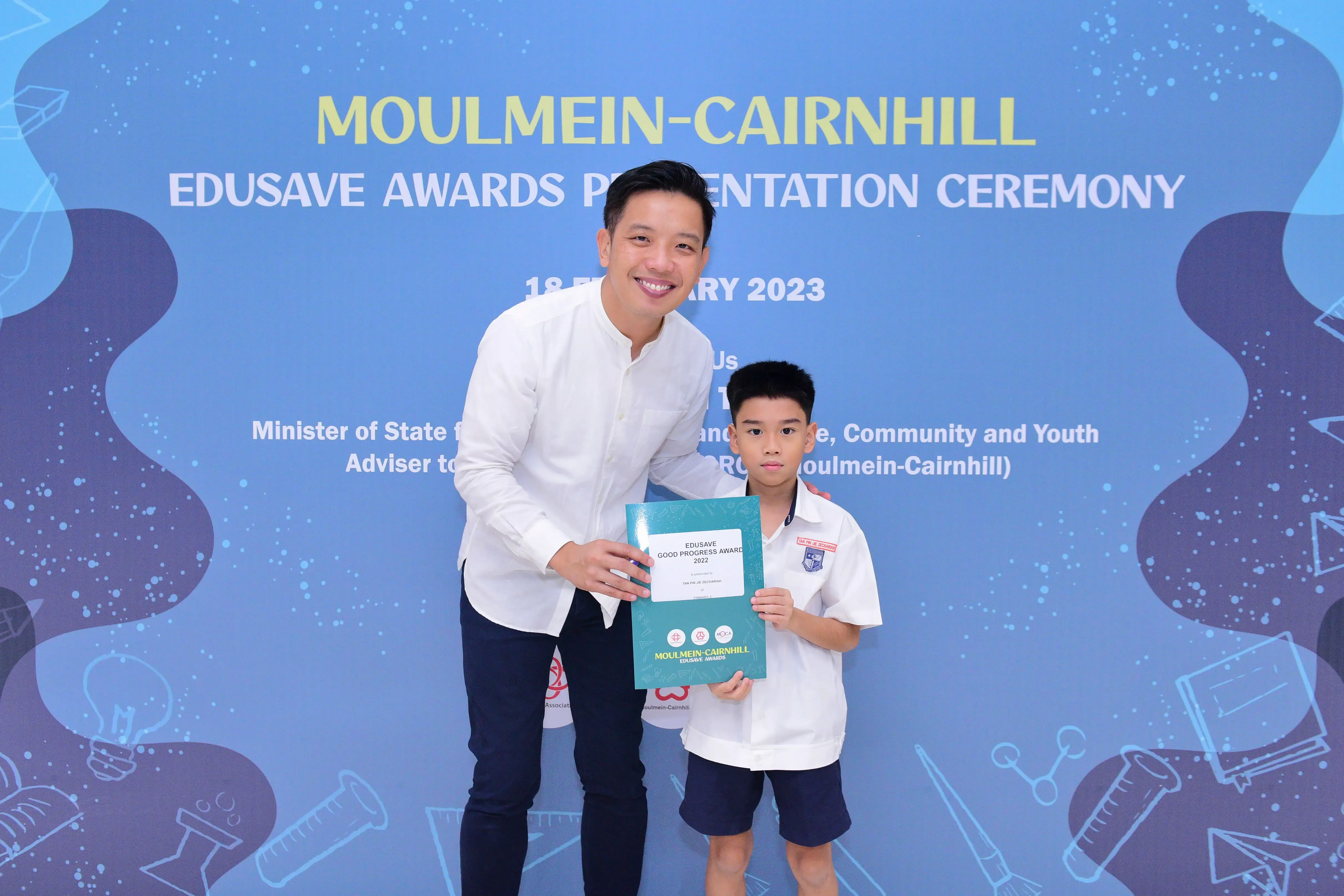 A man and a young boy hold an Edusave Good Progress Award certificate at the Moulmein-Cairnhill ceremony in 2023.