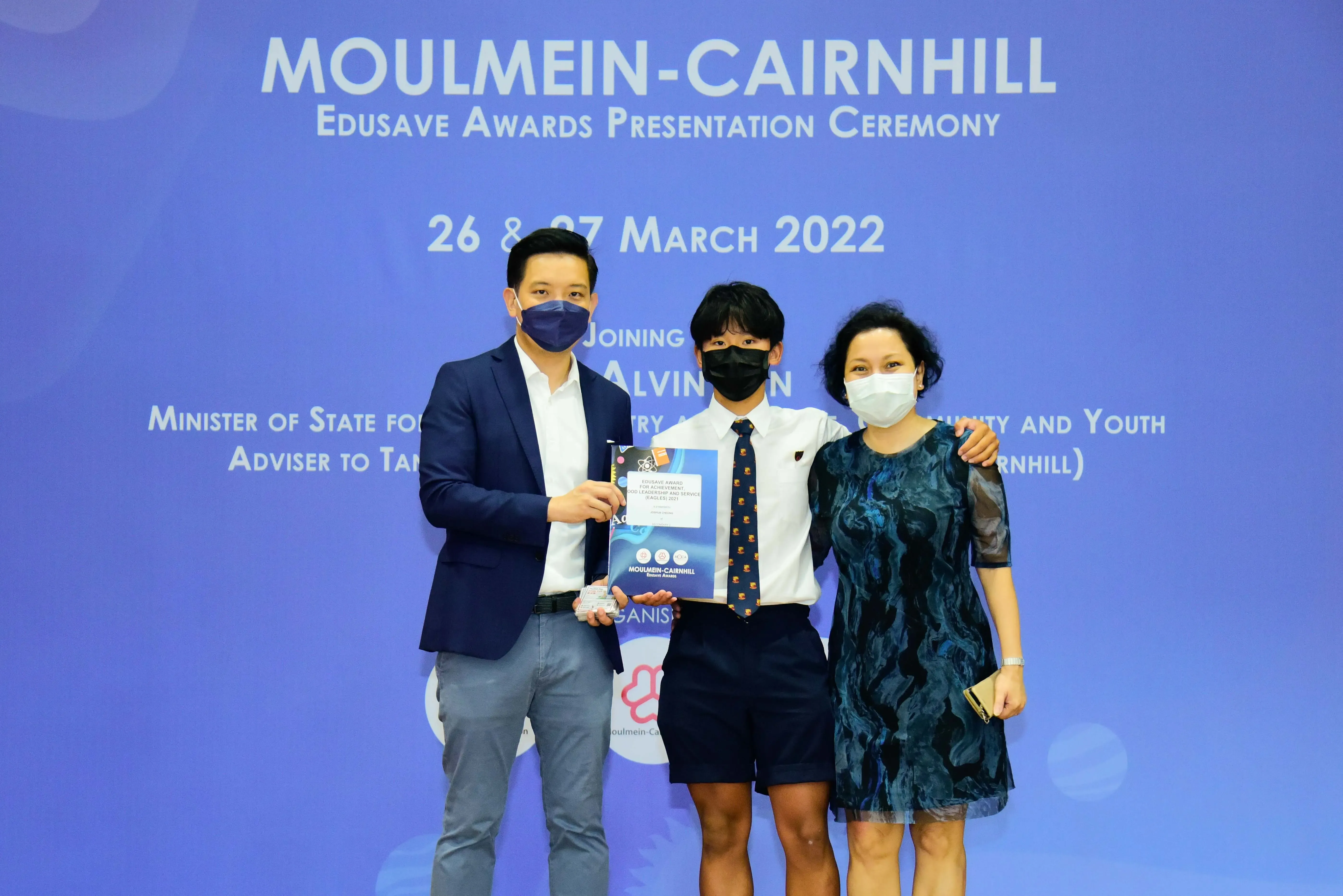 Three masked people pose at the Moulmein-Cairnhill Edusave Awards Presentation Ceremony on 26-27 March 2022.