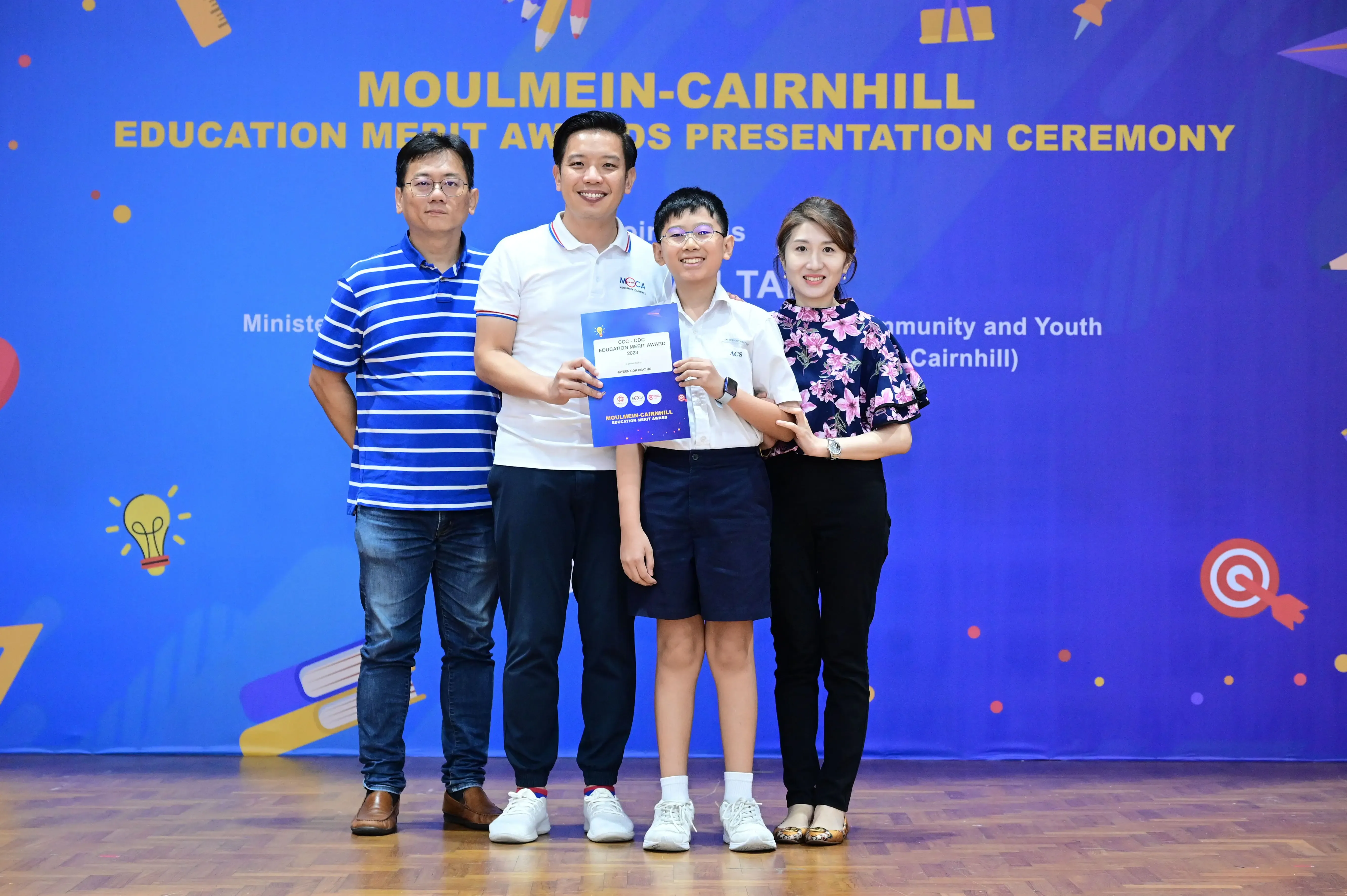 Four people posing at the Moulmein-Cairnhill Education Merit Awards Presentation Ceremony, holding a certificate.