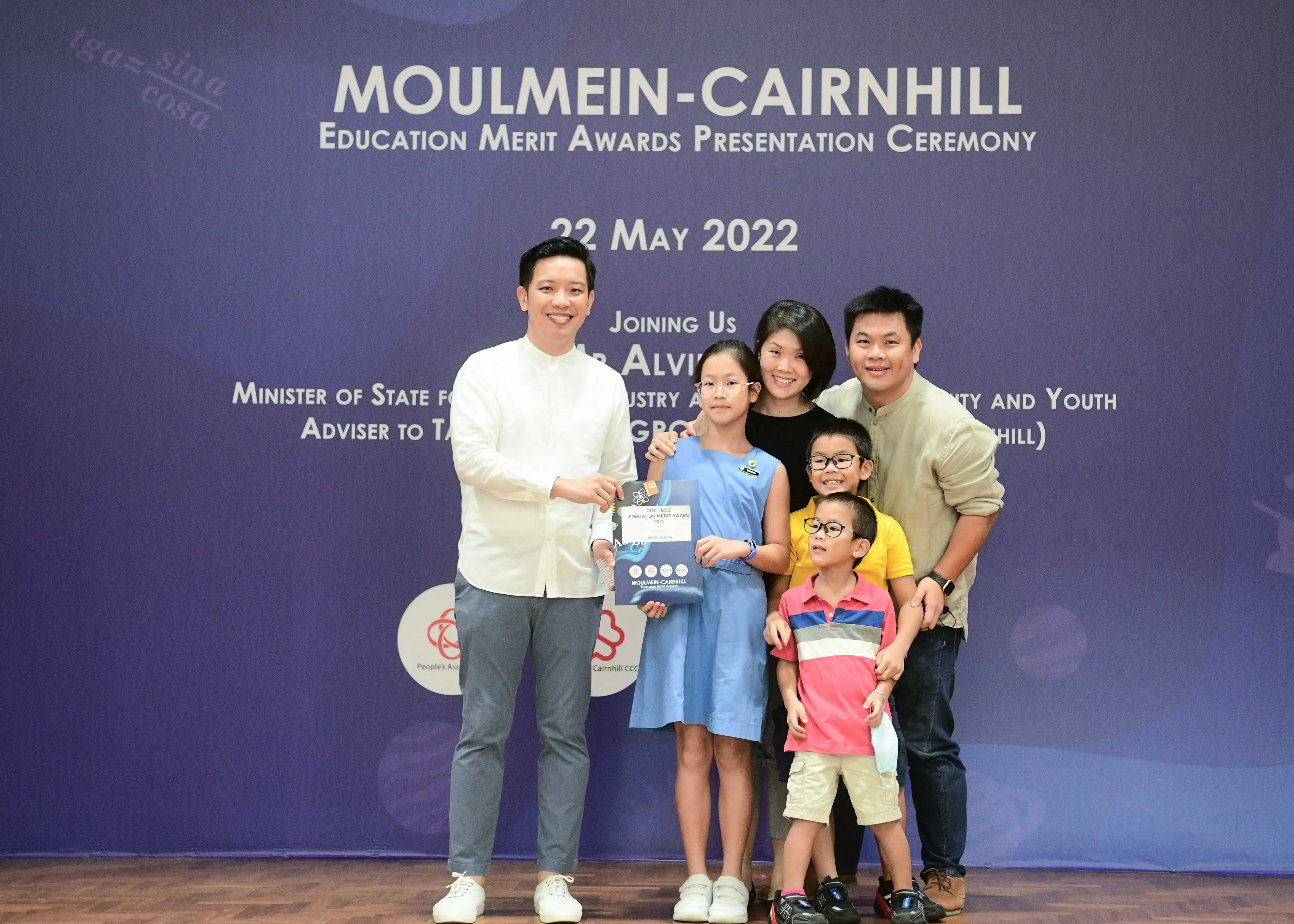 A man presents an award to a girl with her family at the Moulmein-Cairnhill Education Merit Awards on 22 May 2022.