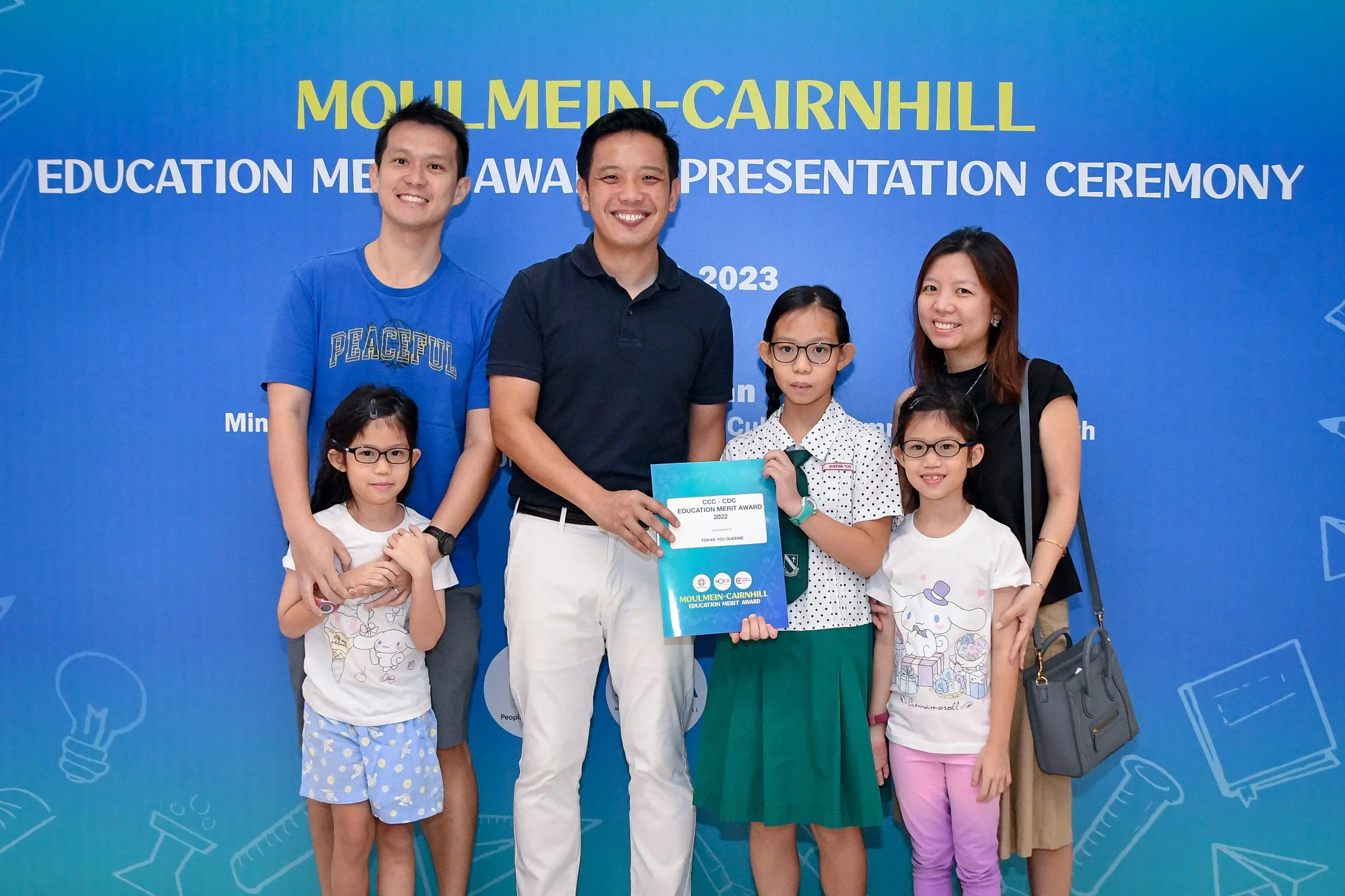 Two men, a woman, and three girls pose at the 2023 Moulmein-Cairnhill Education Merit Award ceremony.
