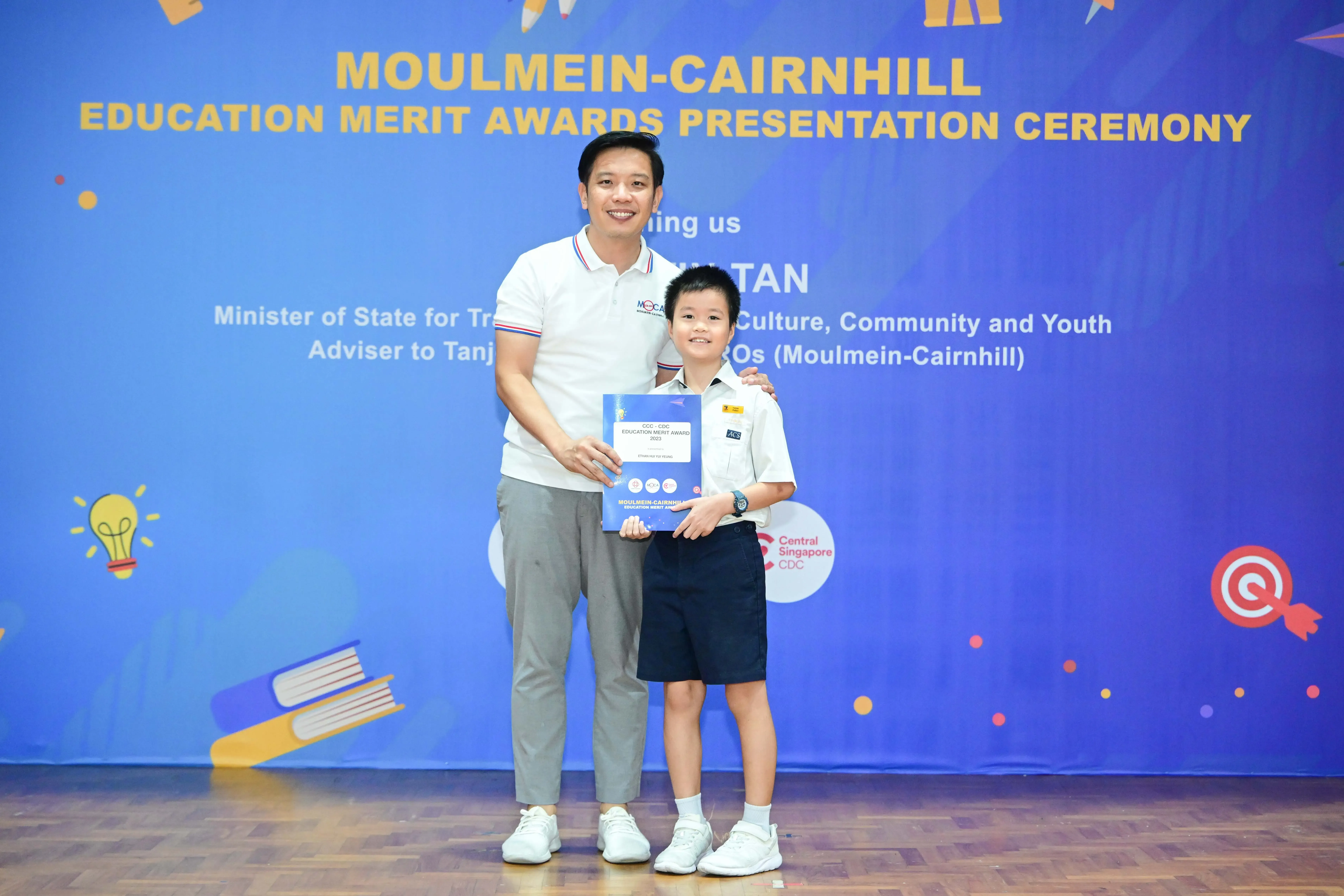 Man and young boy pose holding a certificate at the Moulmein-Cairnhill Education Merit Awards Presentation Ceremony.