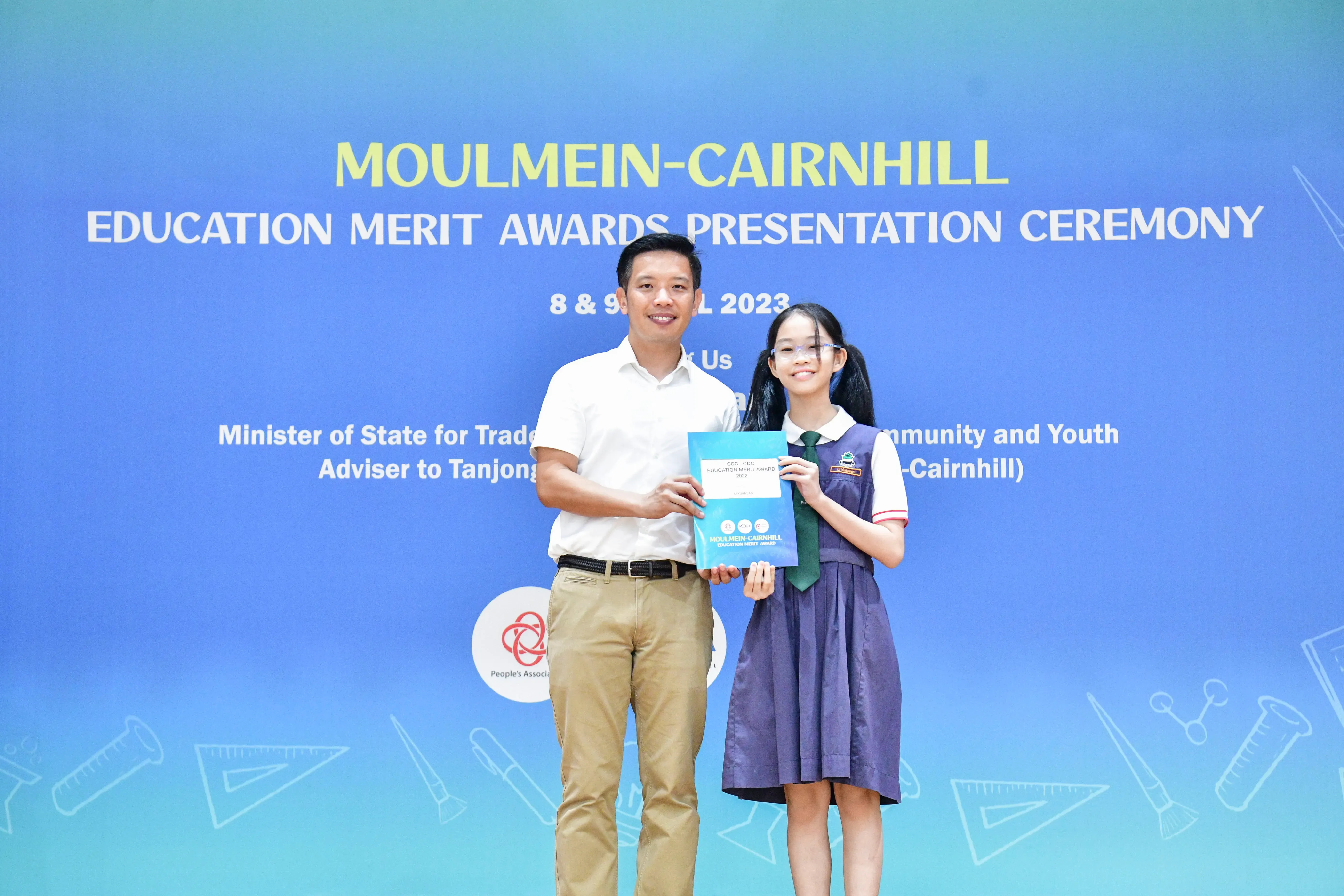 A man and a young girl in school uniform hold a certificate at the Moulmein-Cairnhill Education Merit Awards 2023.