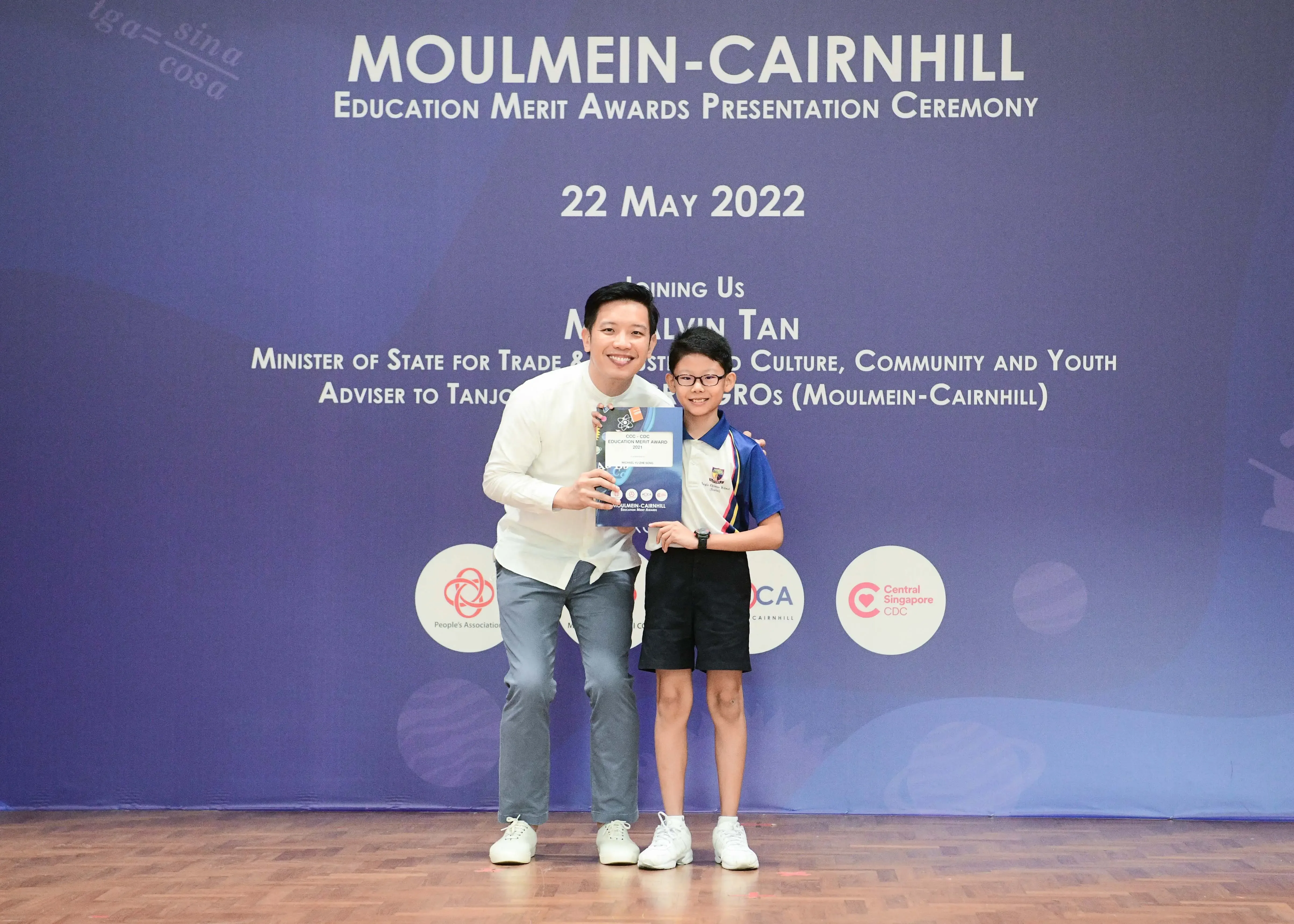 Adult and child pose holding an award at Moulmein-Cairnhill Education Merit Awards Ceremony, 22 May 2022.