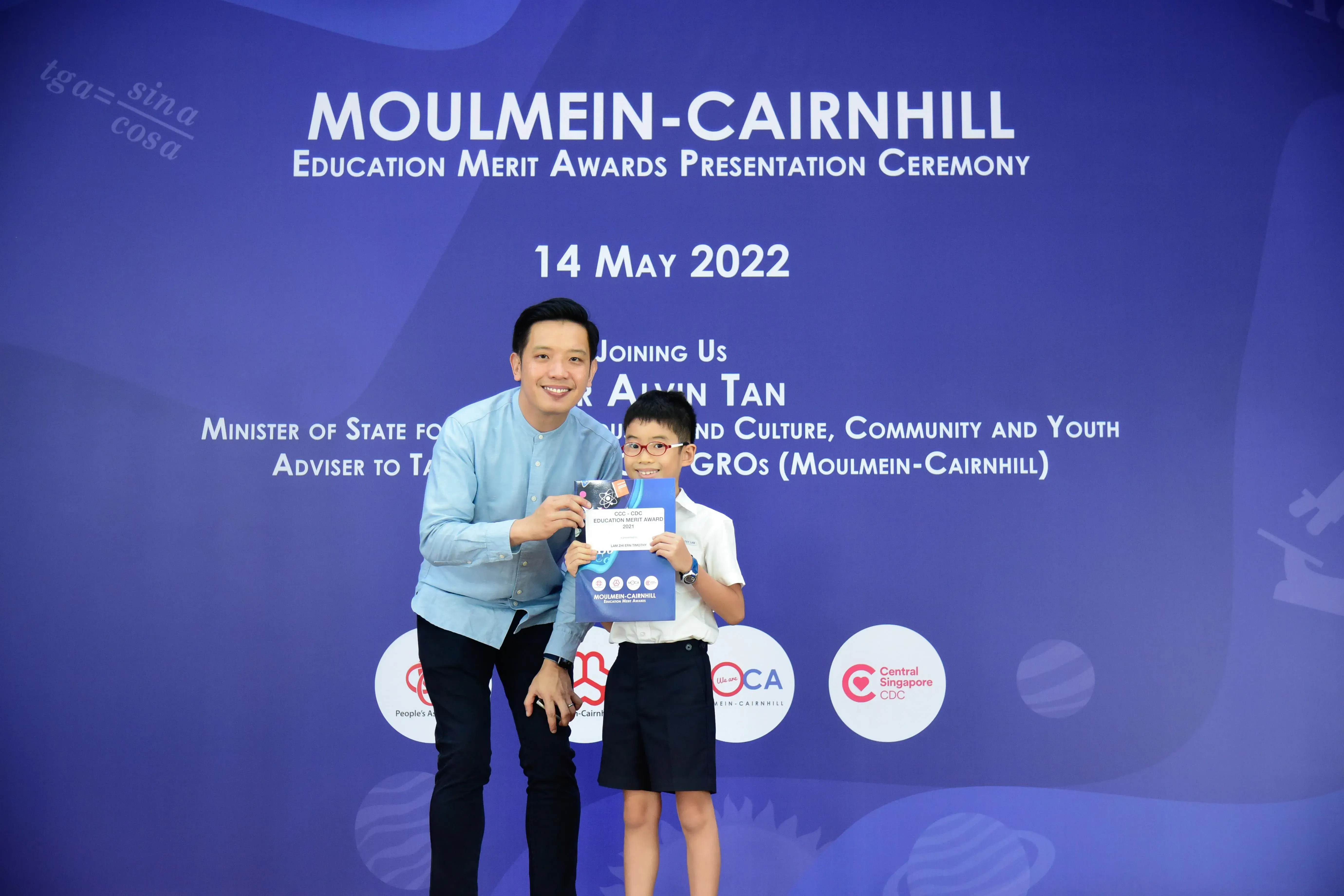 A man and a young boy hold an award certificate at the Moulmein-Cairnhill Education Merit Awards on 14 May 2022.