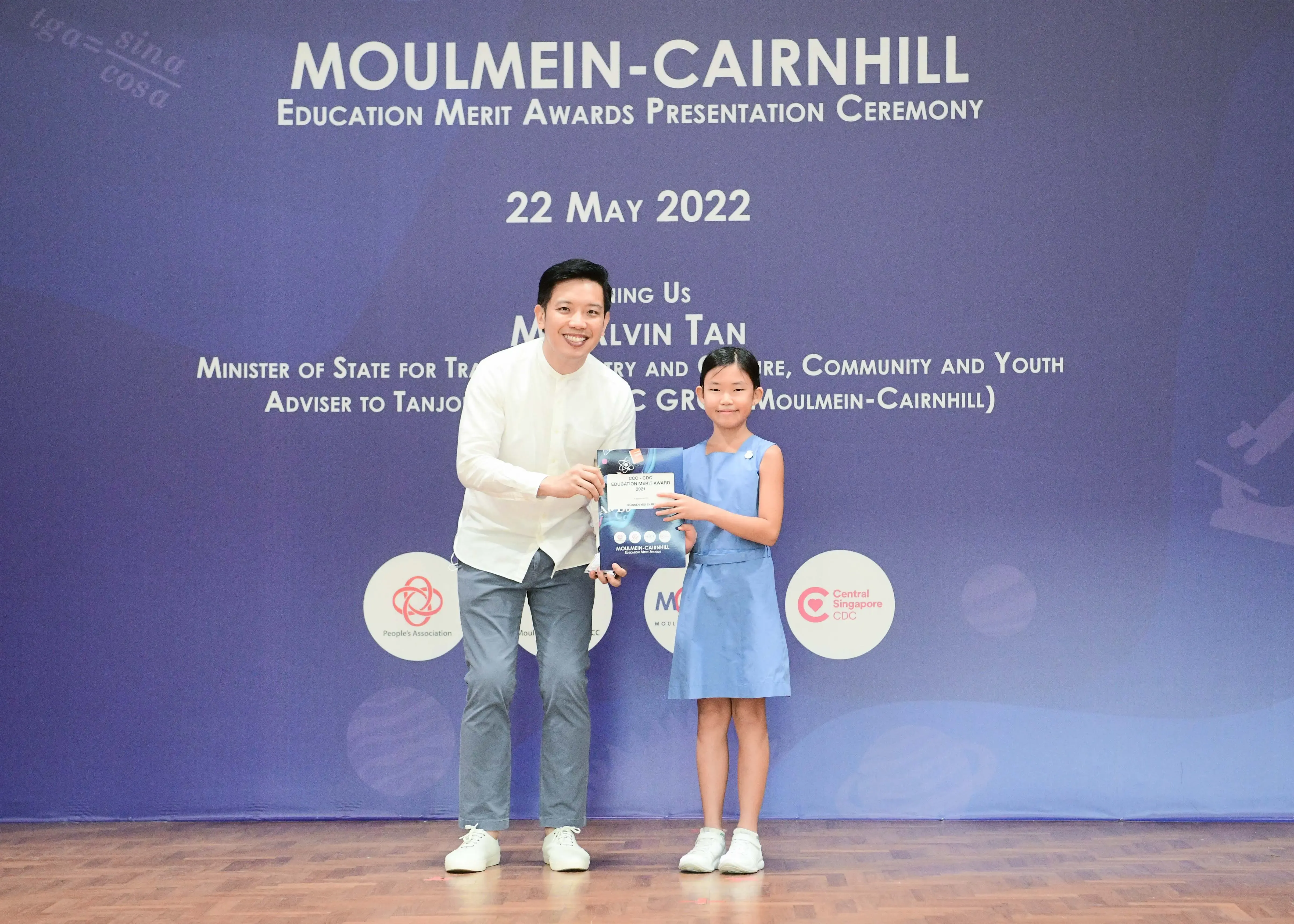 A man and a young girl hold an award certificate at the Moulmein-Cairnhill Education Merit Awards Ceremony on 22 May 2022.