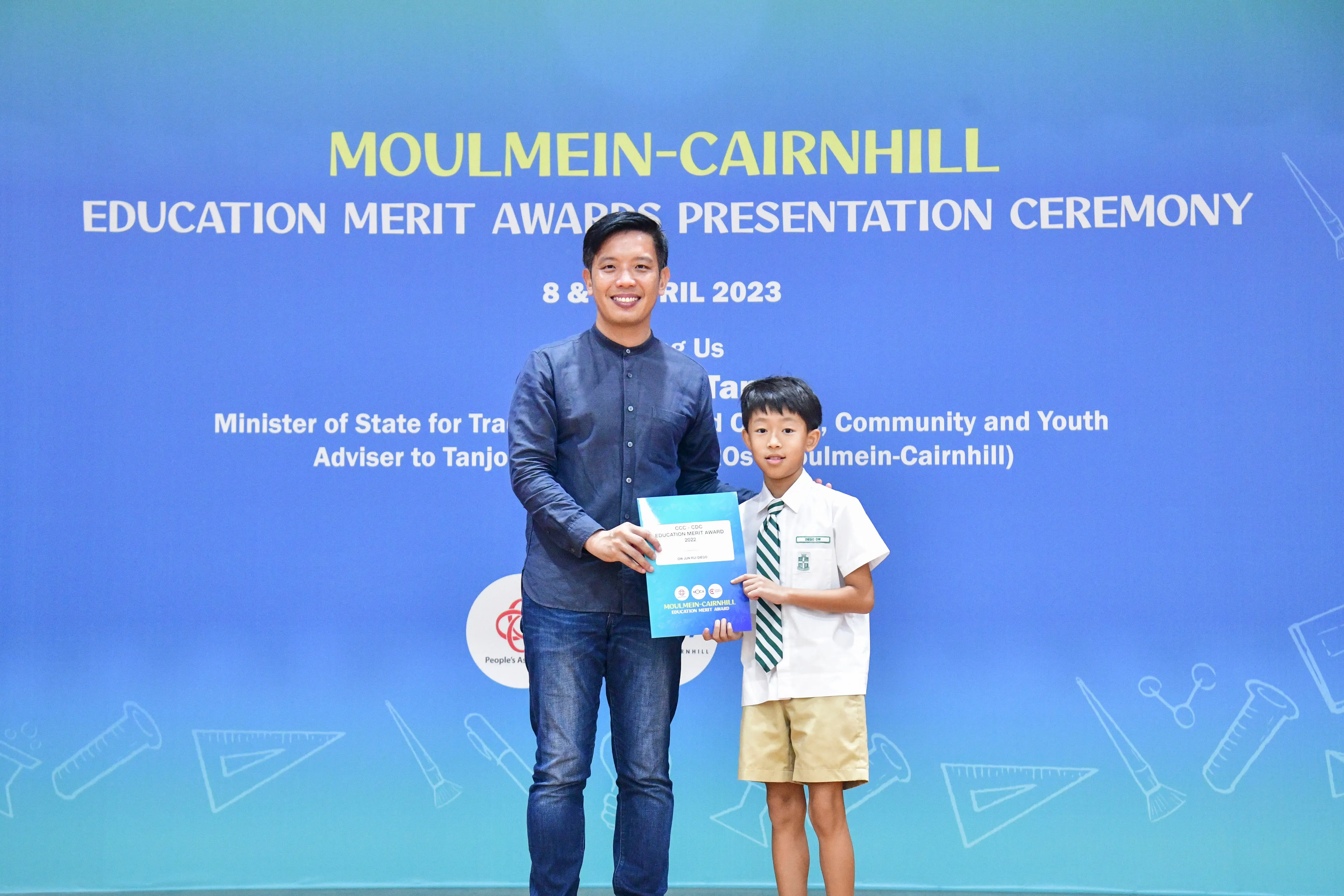 A man and a young boy in school uniform hold an award certificate at the Moulmein-Cairnhill Education Merit Awards 2023.