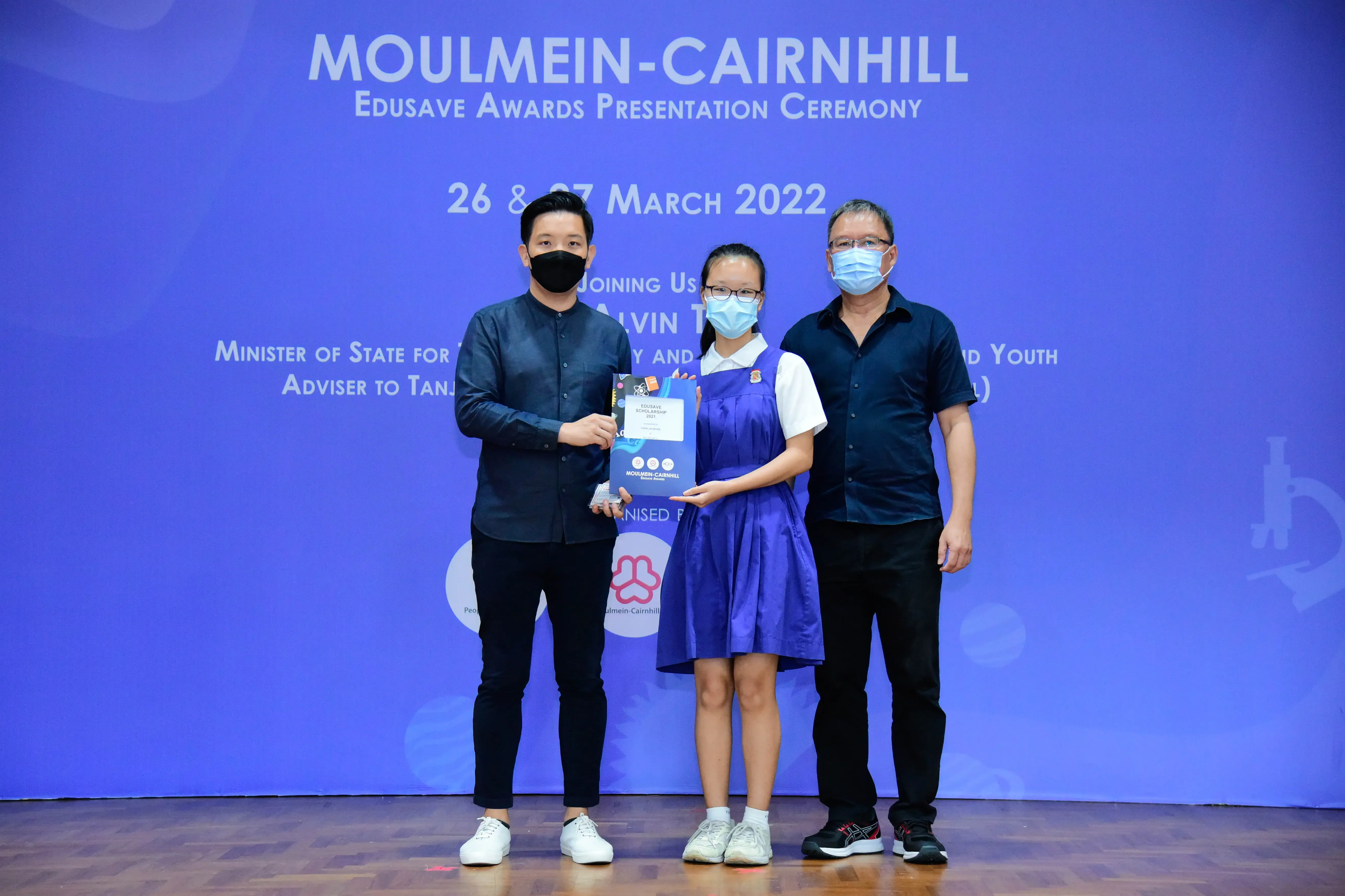 Three masked people pose at the Moulmein-Cairnhill Edusave Awards Ceremony on 26-27 March 2022.