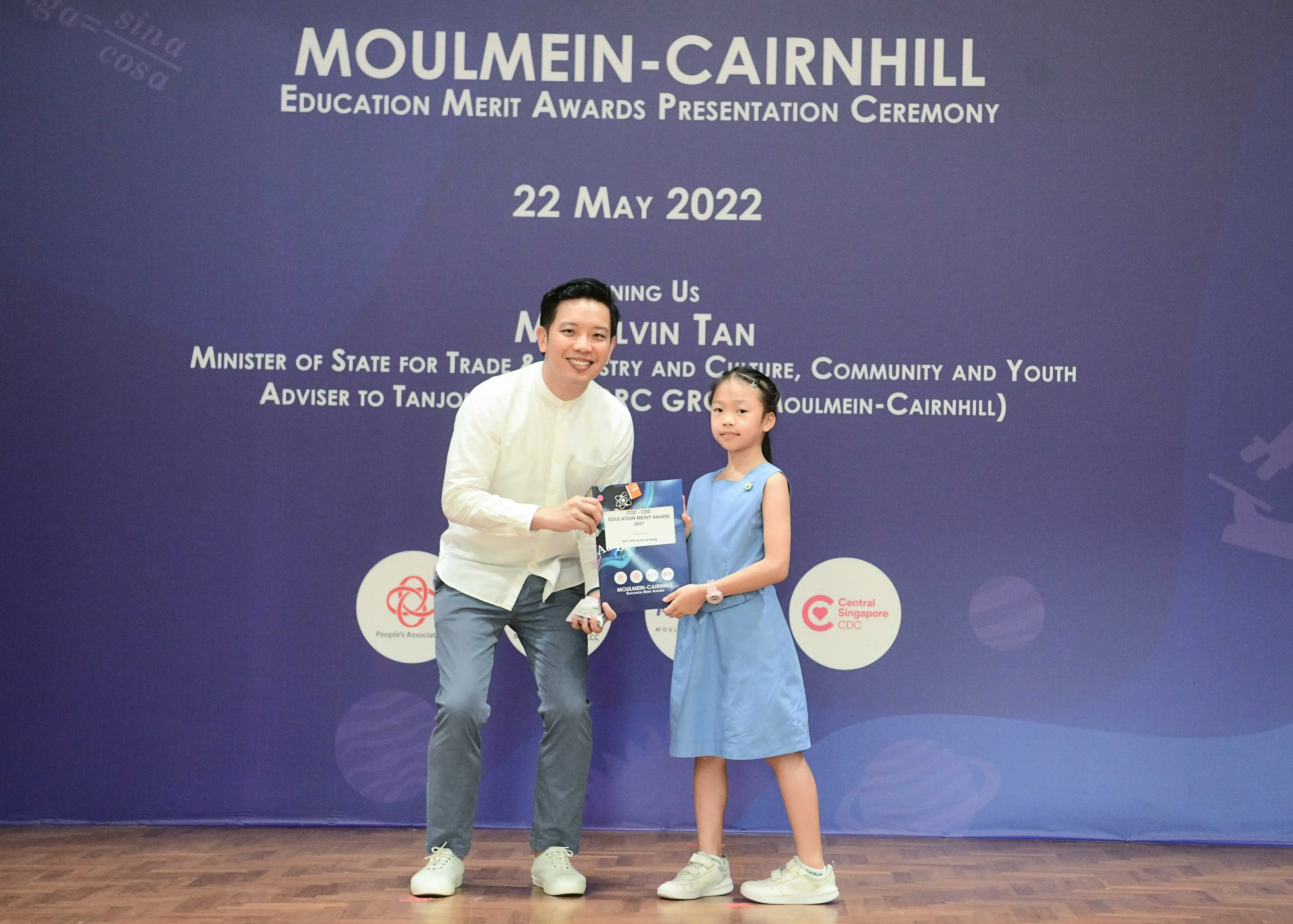 A man and a young girl hold an award certificate at the Moulmein-Cairnhill Education Merit Awards on 22 May 2022.