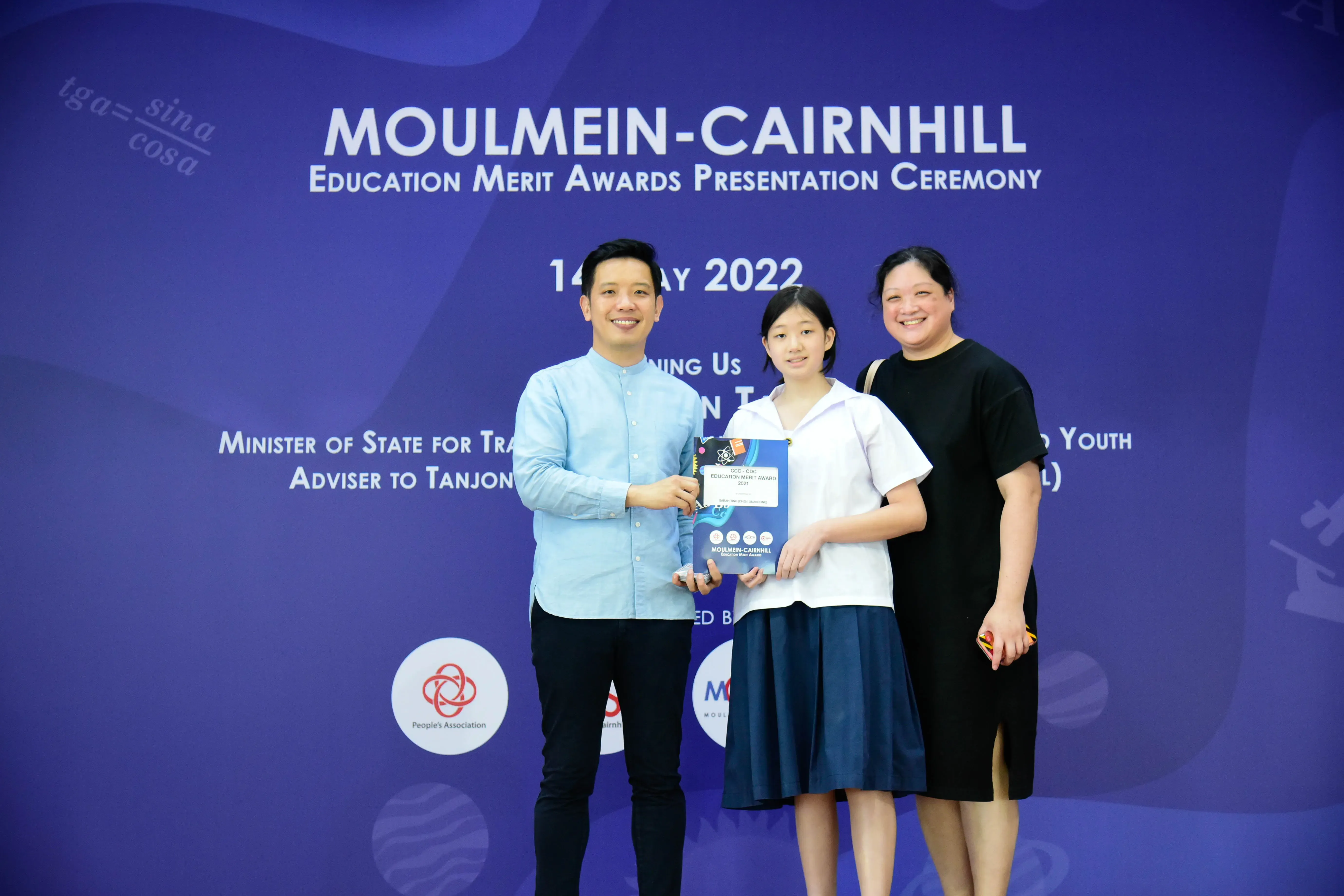 Three people pose with an award at the Moulmein-Cairnhill Education Merit Awards Presentation Ceremony in 2022.