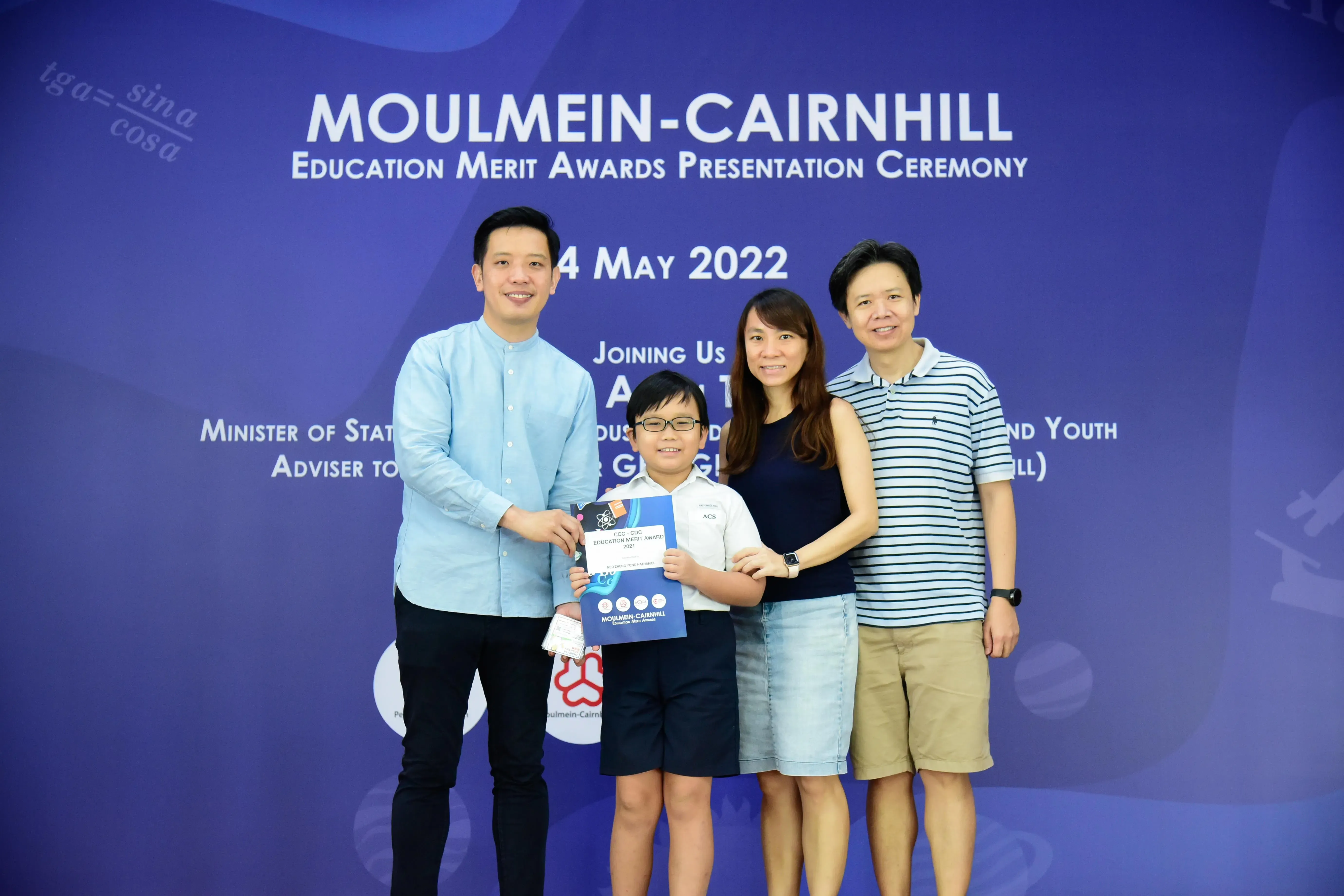 Three adults and a boy holding a certificate pose at the Moulmein-Cairnhill Education Merit Awards, May 2022.