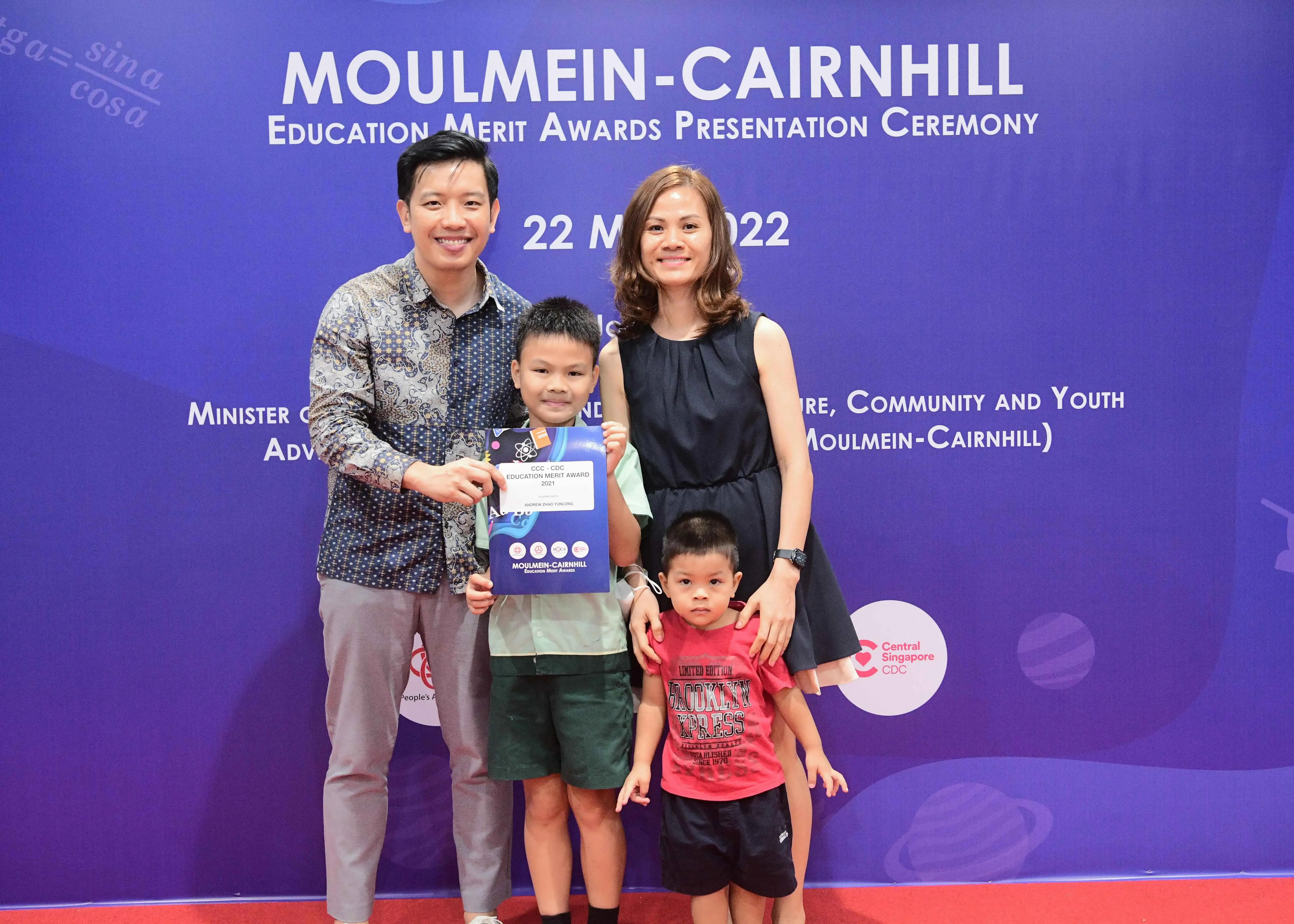 Family of four posing with an award certificate at the Moulmein-Cairnhill Education Merit Awards Ceremony 2022.
