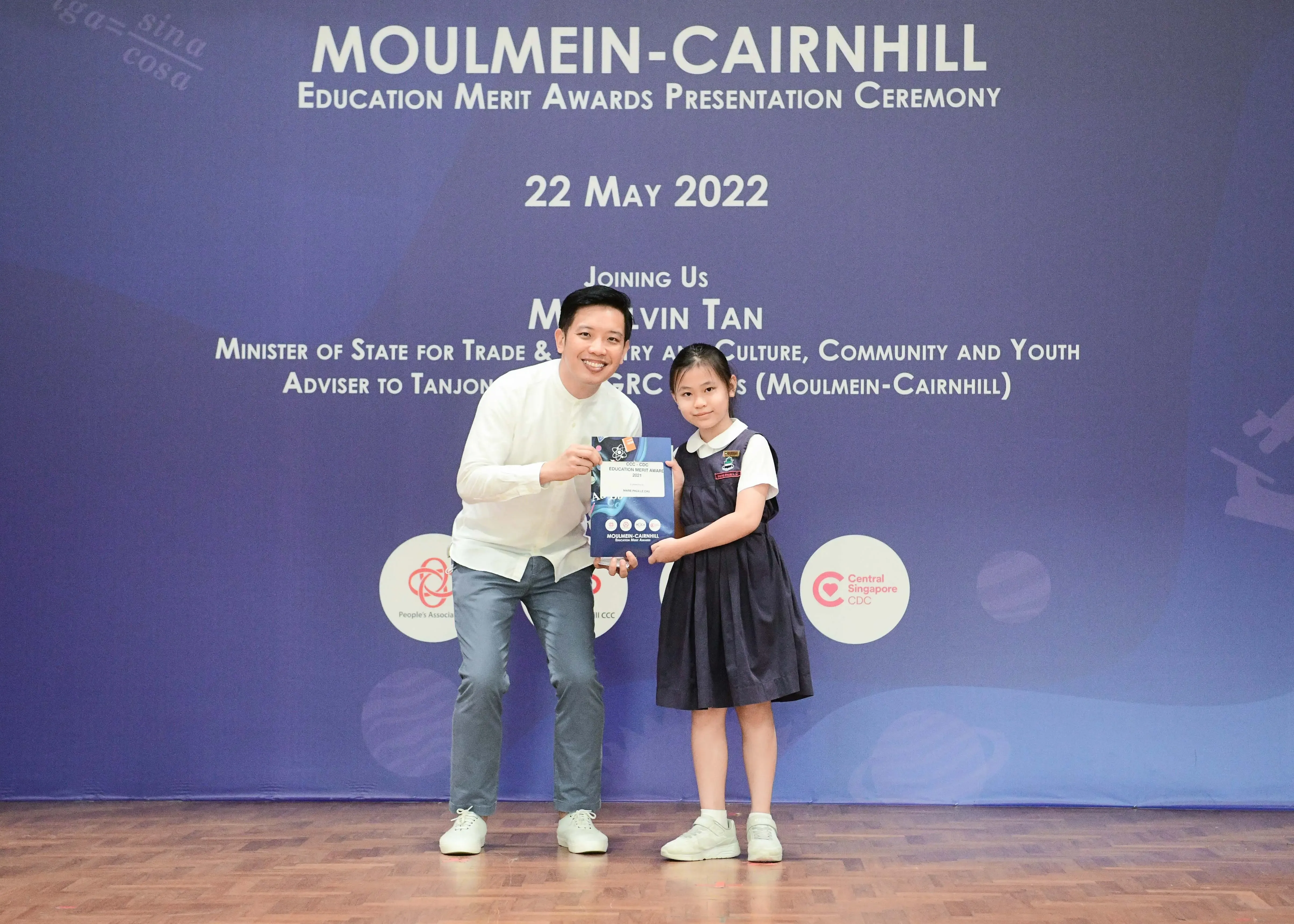A man and a young girl hold an award together at the Moulmein-Cairnhill Education Merit Awards ceremony on 22 May 2022.