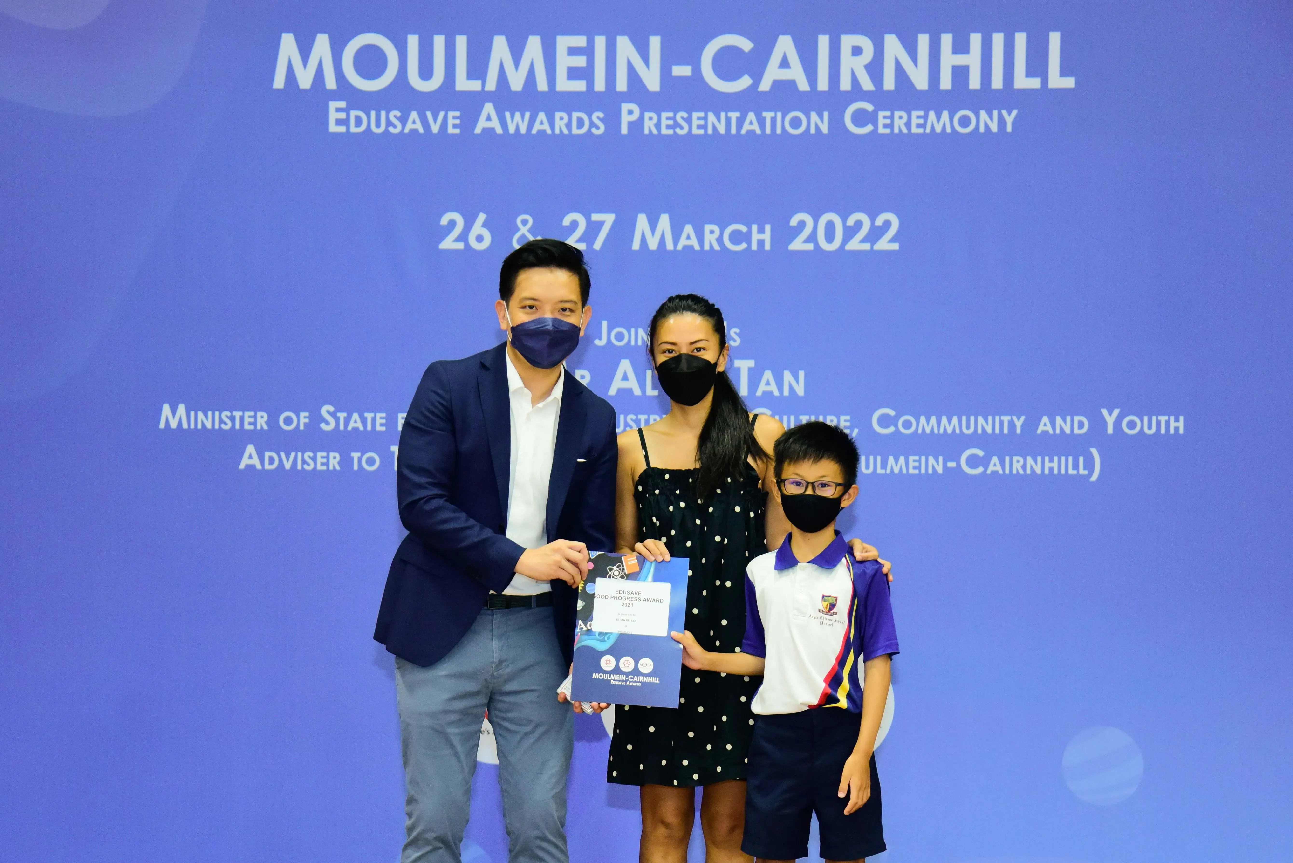 Three masked people pose with an award certificate at the Moulmein-Cairnhill Edusave Awards Ceremony, March 2022.