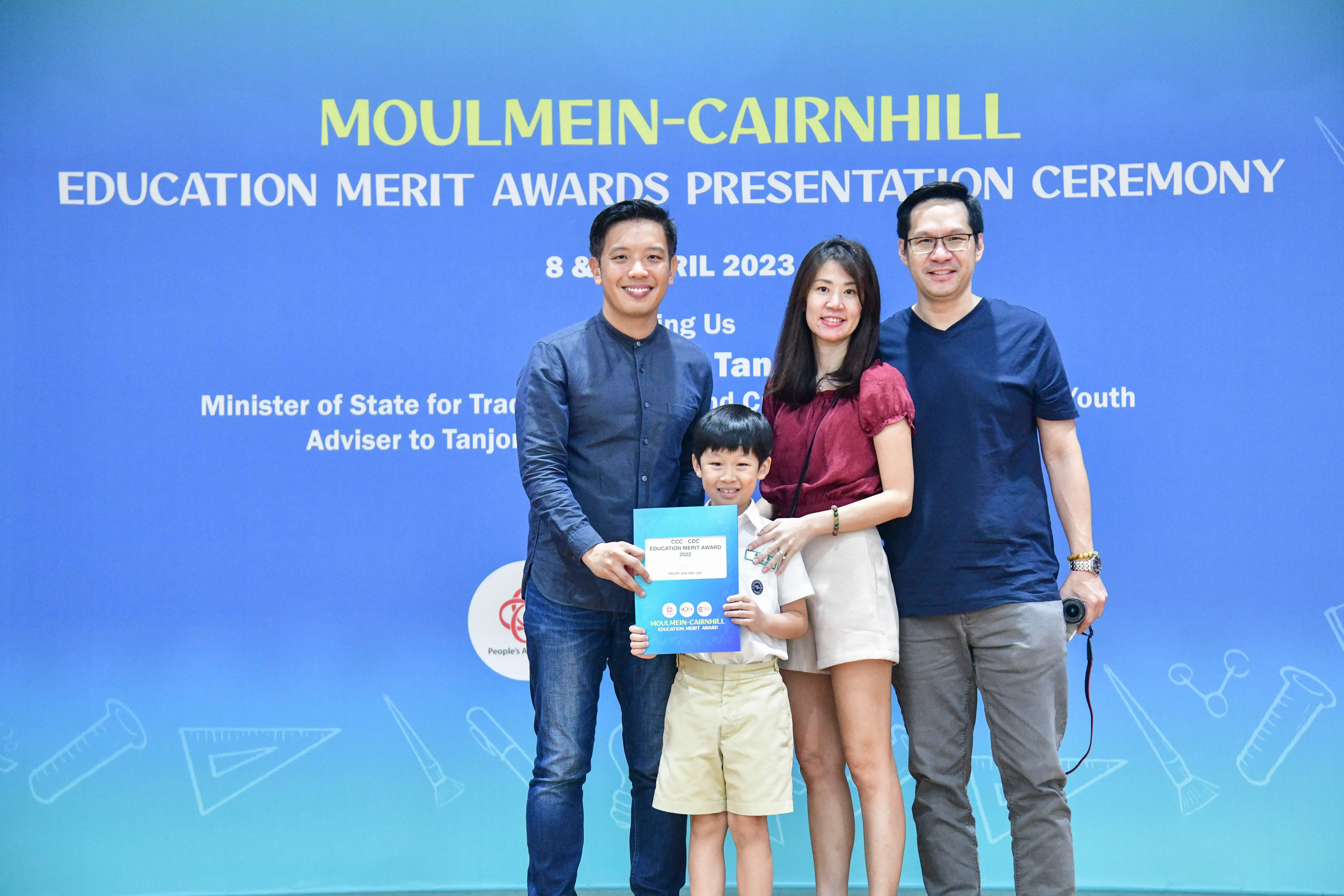 Three adults and a young boy pose with an award certificate at the Moulmein-Cairnhill Education Merit Awards 2023.