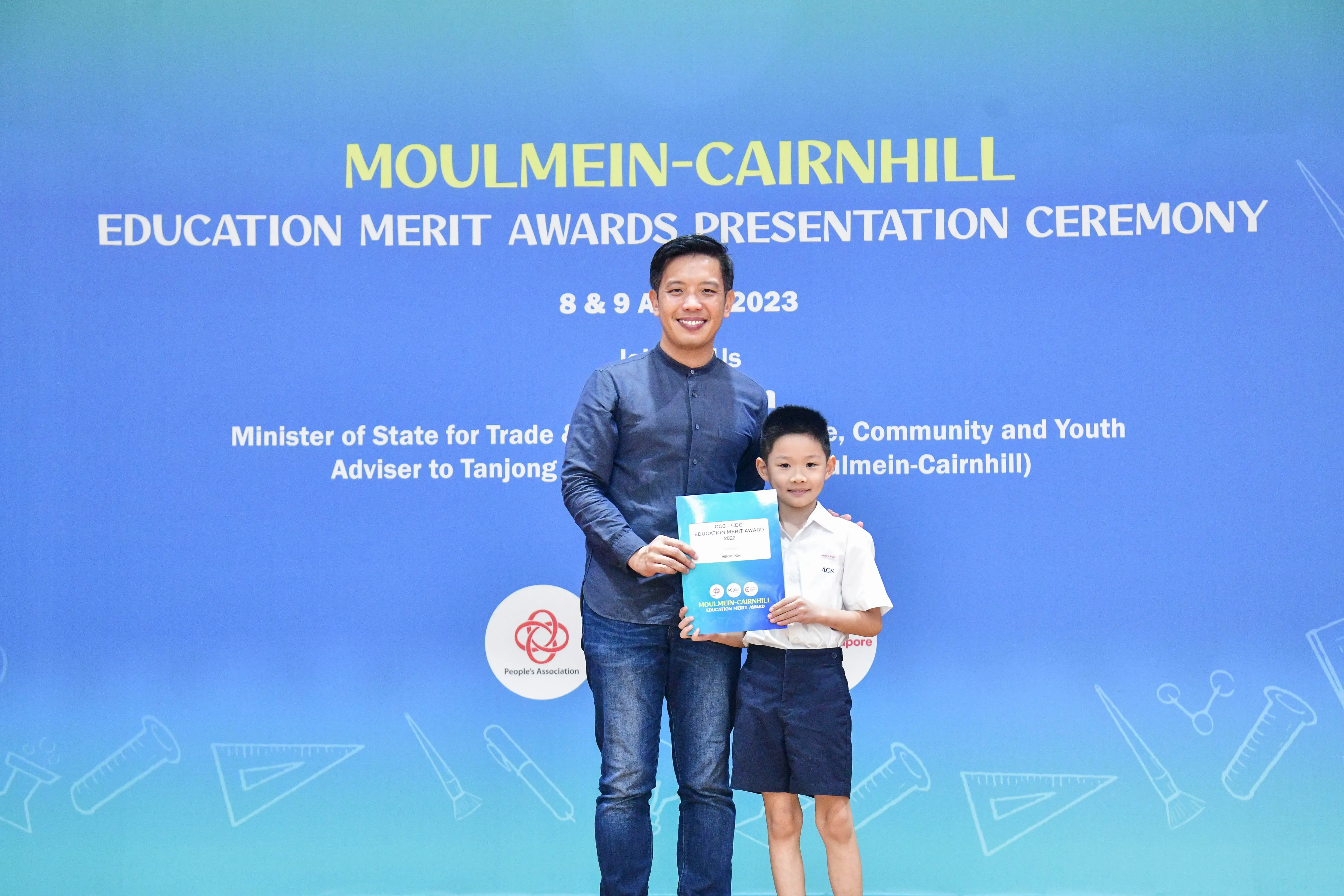 A man and a young boy hold a certificate together at the Moulmein-Cairnhill Education Merit Awards Ceremony 2023.