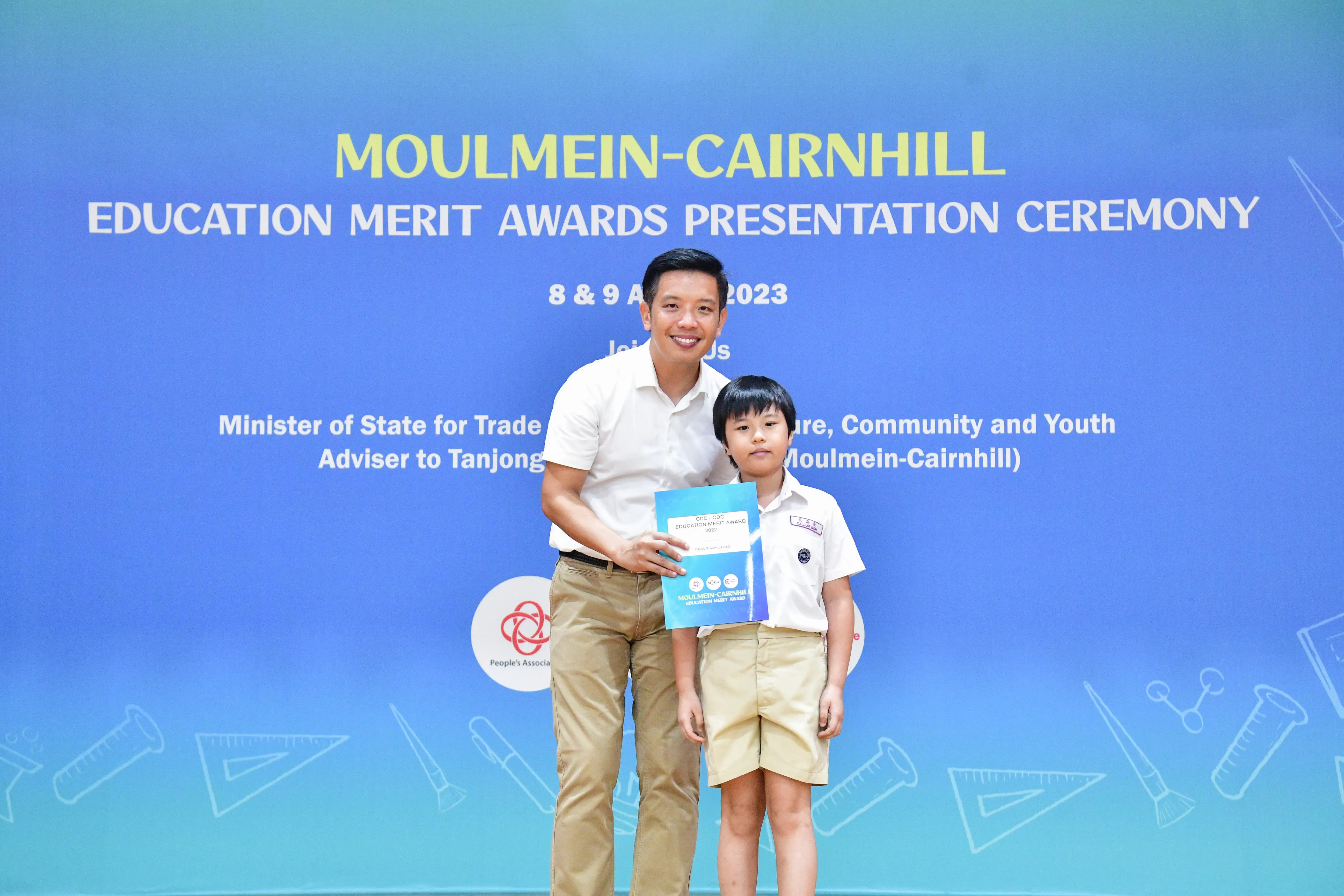 A man and a young student pose together holding a certificate at the Moulmein-Cairnhill Education Merit Awards 2023.