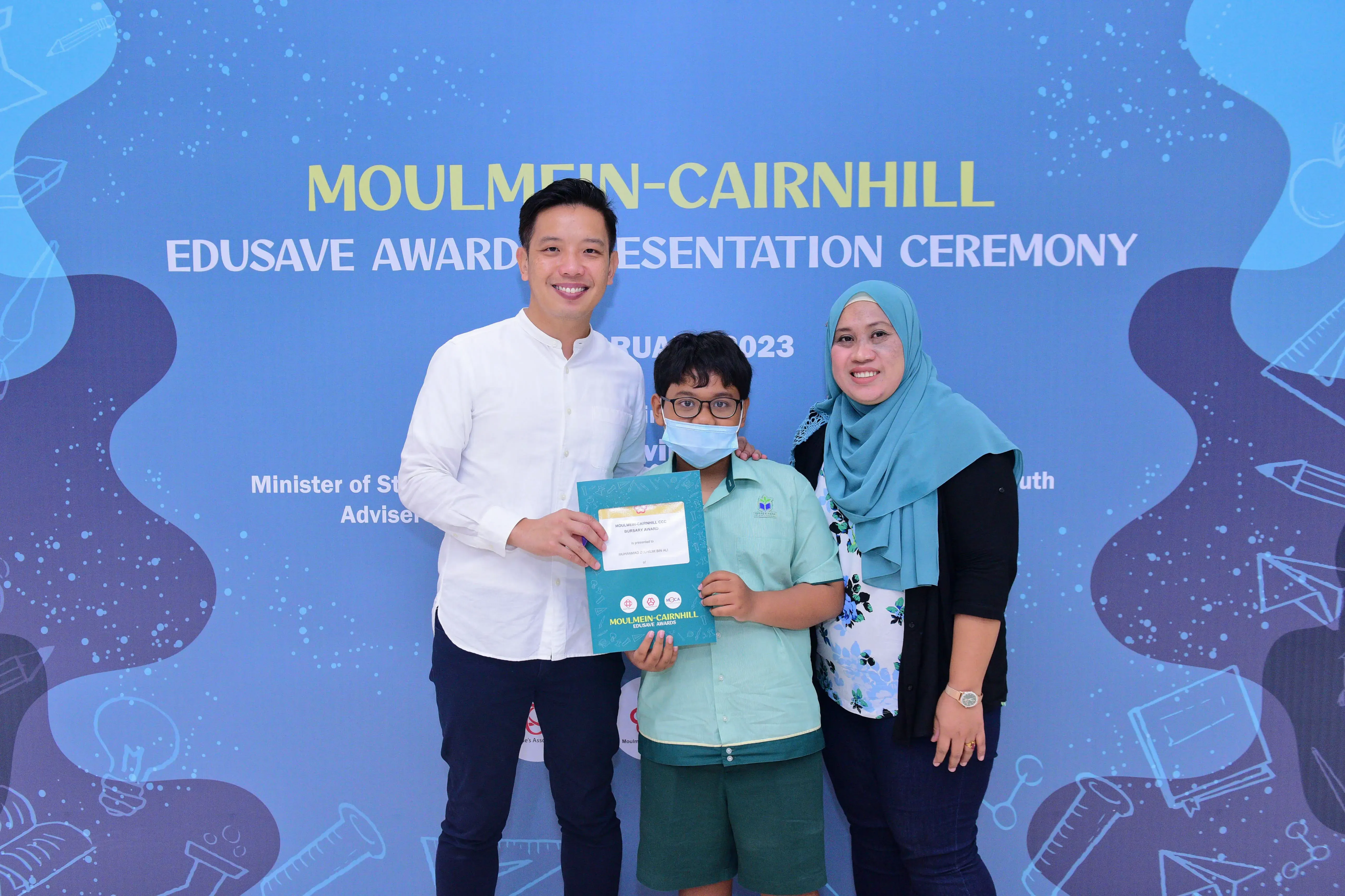 Three people pose with a certificate at the Moulmein-Cairnhill Edusave Awards Presentation Ceremony 2023.