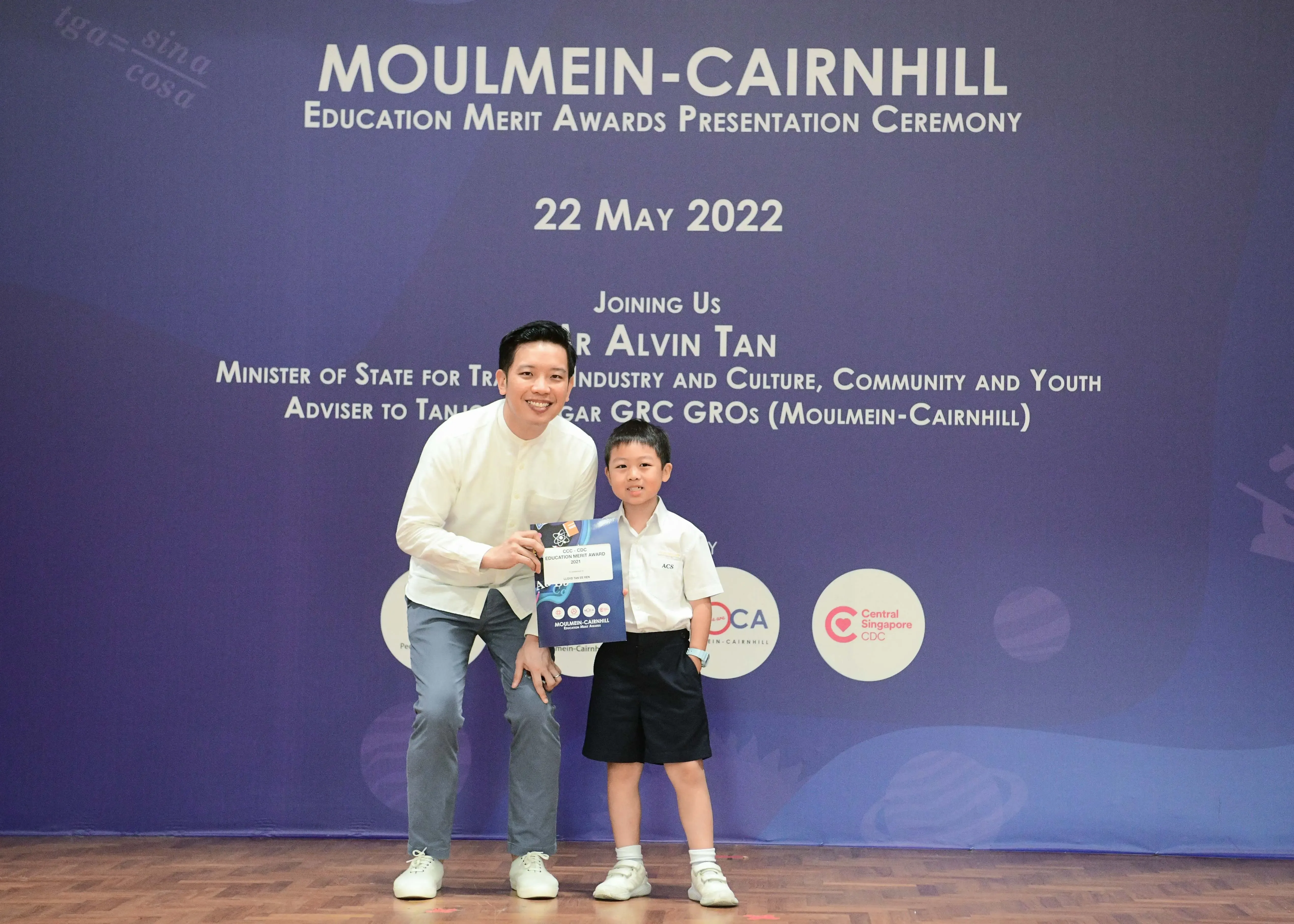 A man and a young boy pose holding an award certificate at the Moulmein-Cairnhill Education Merit Awards on 22 May 2022.