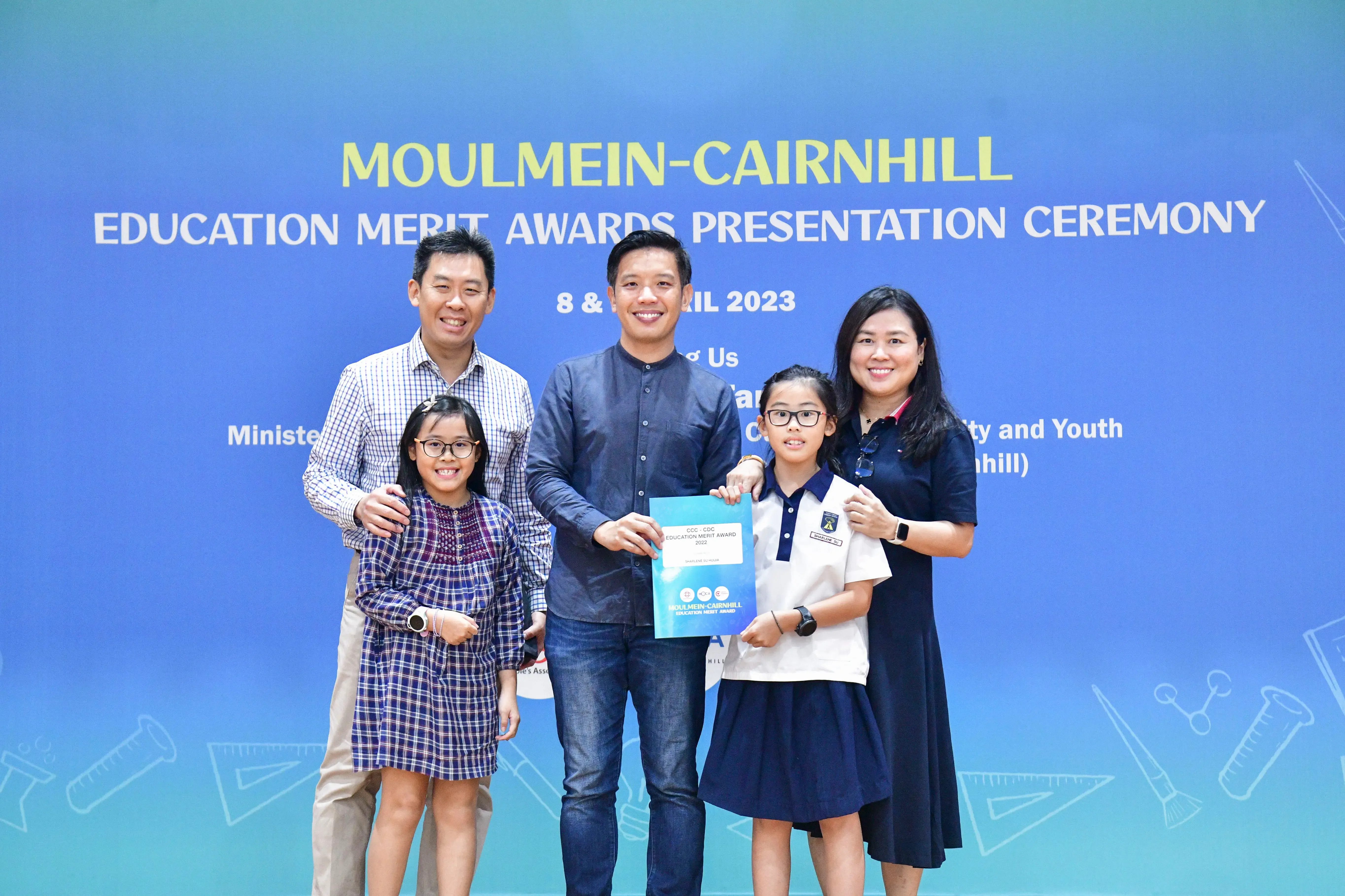 Five people pose holding an award certificate at the Moulmein-Cairnhill Education Merit Awards Ceremony 2023.