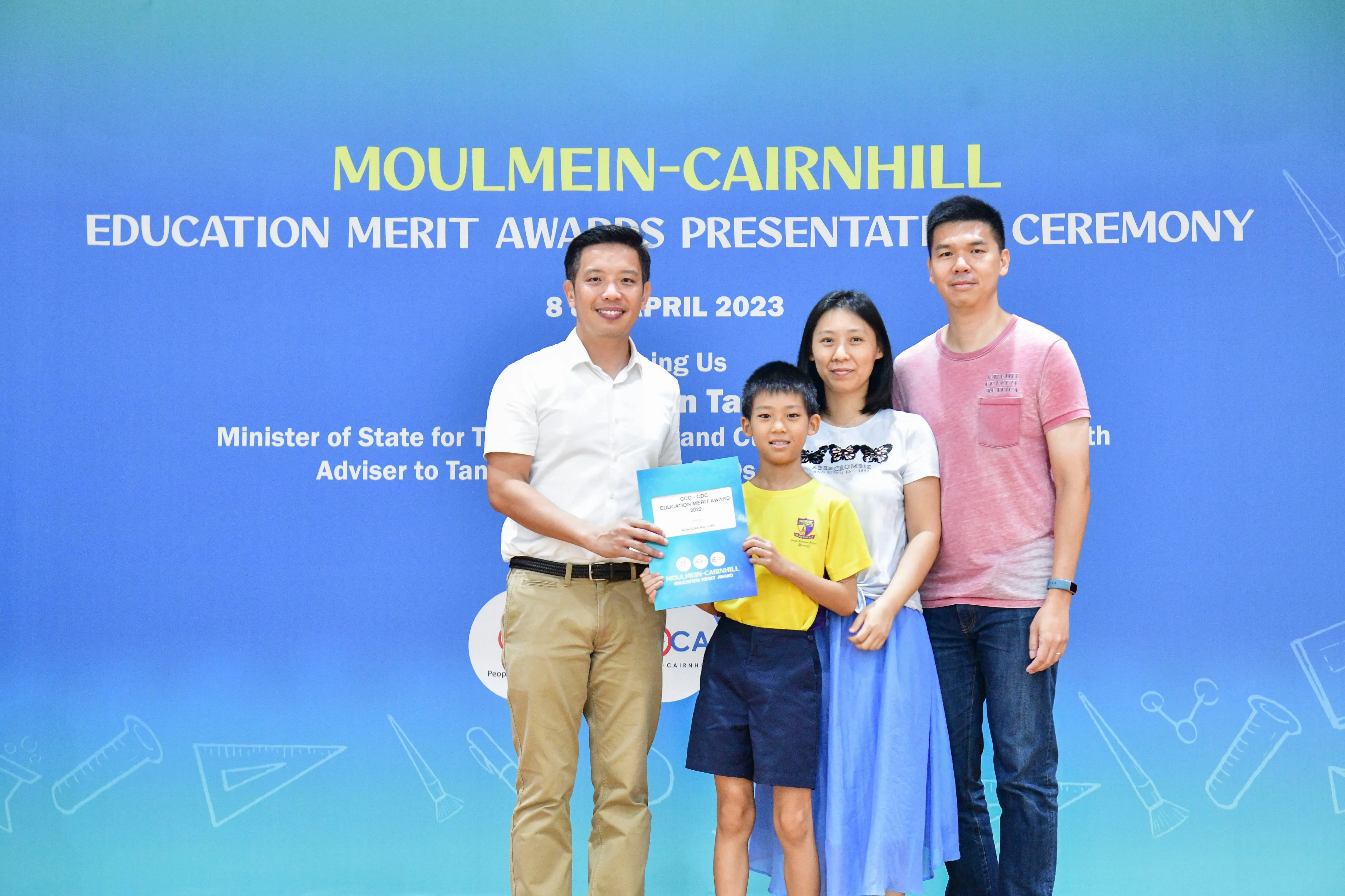 Four people pose with a certificate at the Moulmein-Cairnhill Education Merit Awards Presentation Ceremony, April 2023.