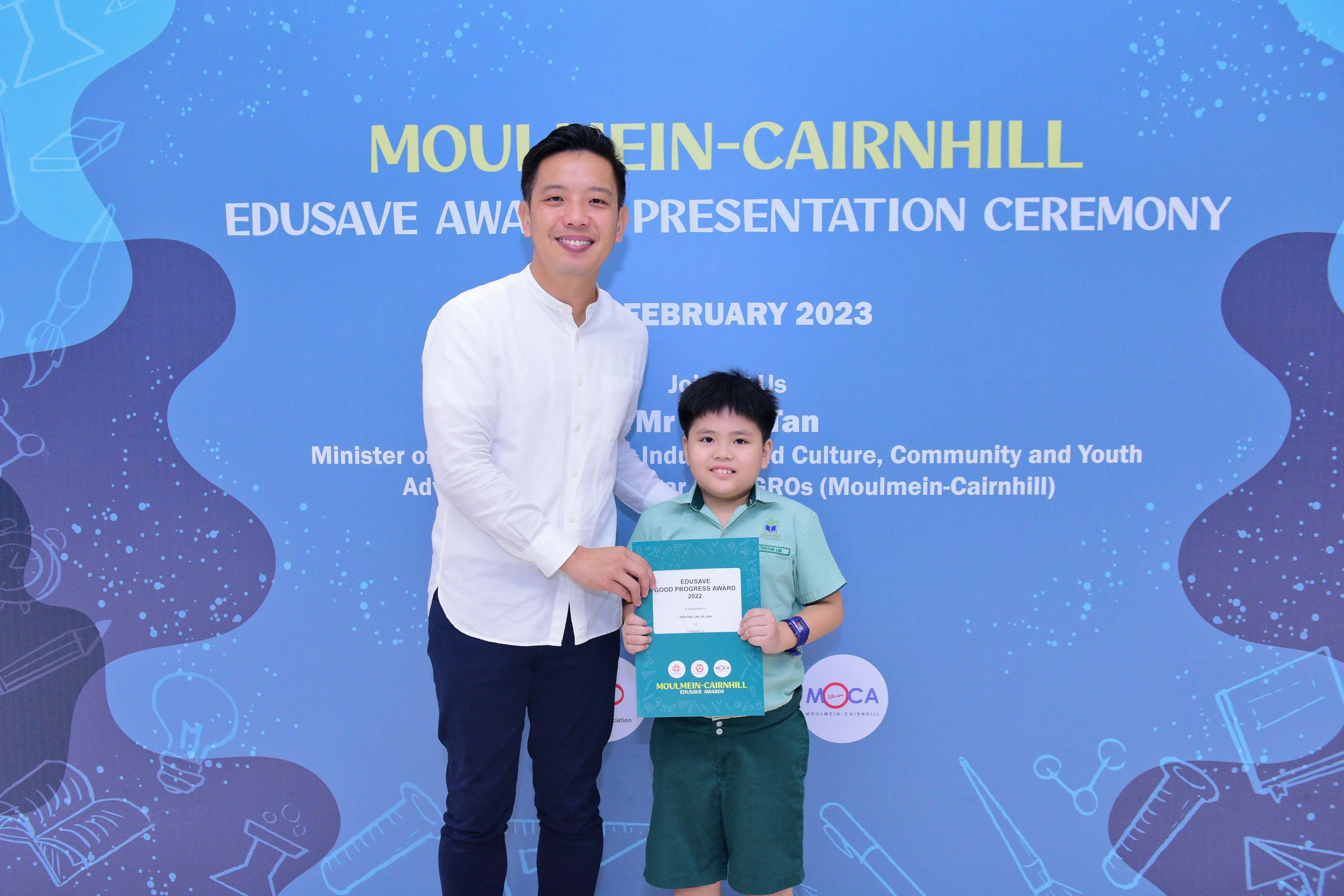 A man and a young boy pose with an award certificate at the Moulmein-Cairnhill Edusave Presentation Ceremony, February 2023.