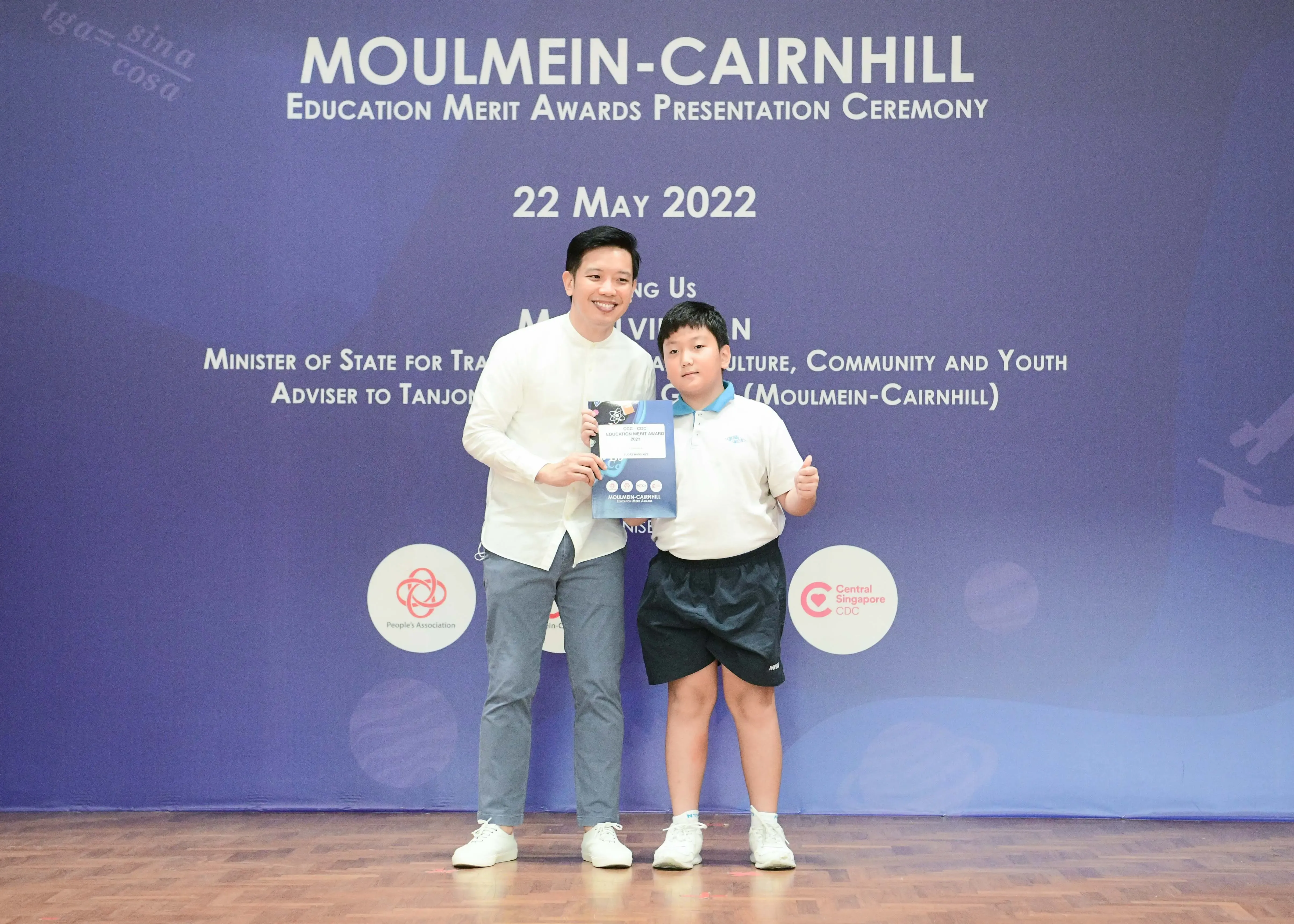 A man and a young boy pose holding an award certificate at the Moulmein-Cairnhill Education Merit Awards on 22 May 2022.