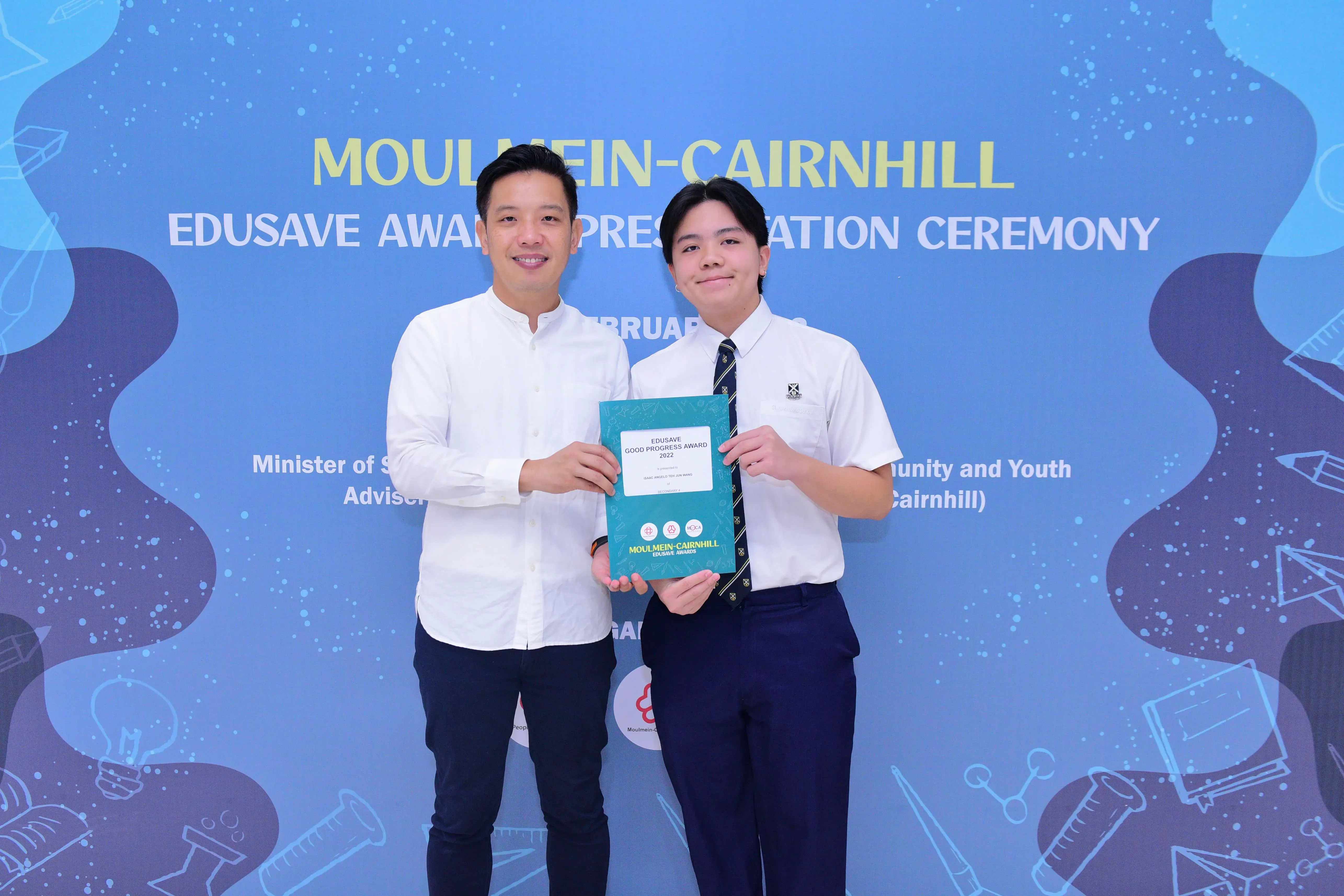 Two people smile holding an Edusave Good Progress Award at the Moulmein-Cairnhill Edusave Awards Ceremony.
