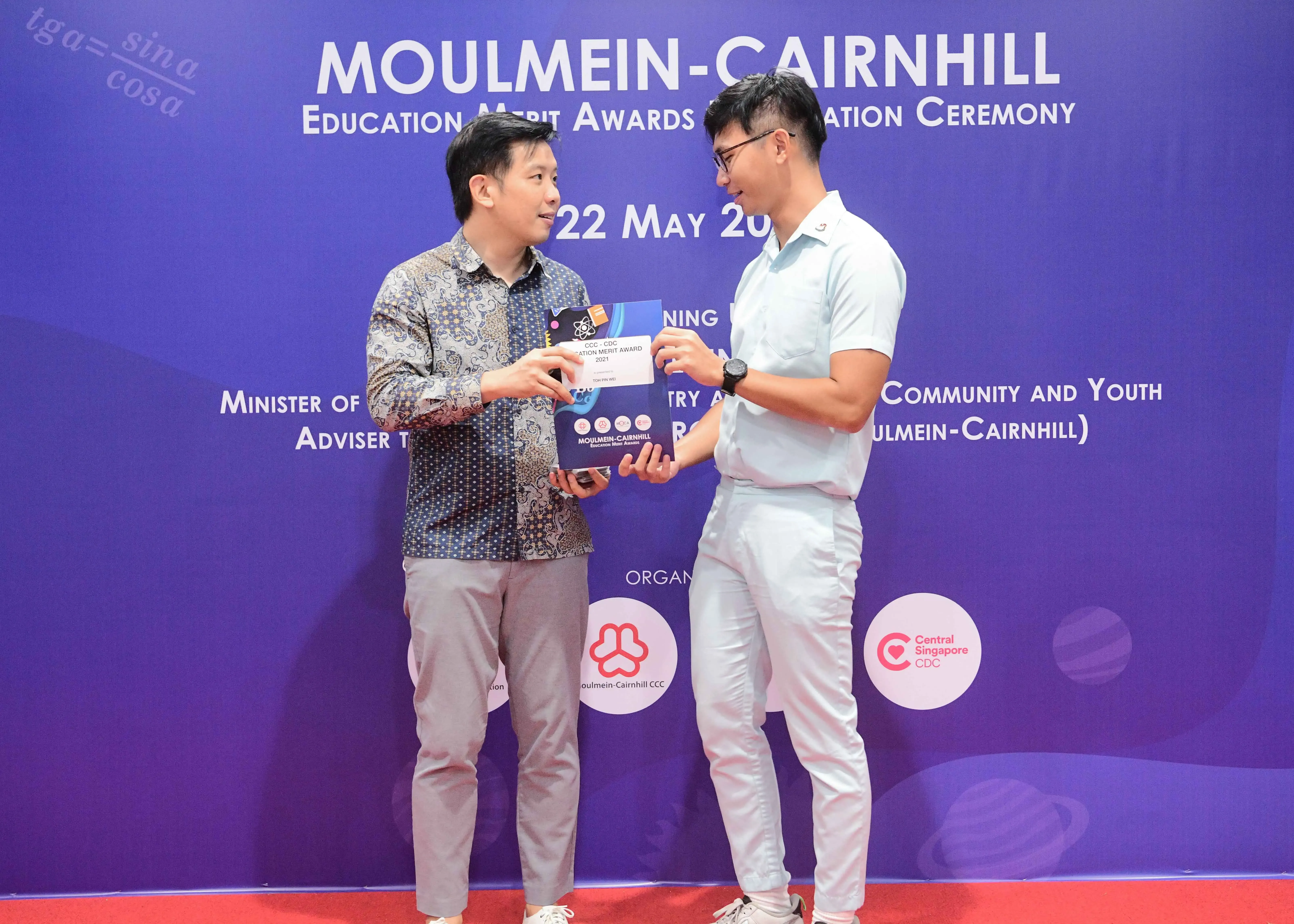 Two men exchange an award certificate at the Moulmein-Cairnhill Education Merit Awards Ceremony on 22 May.