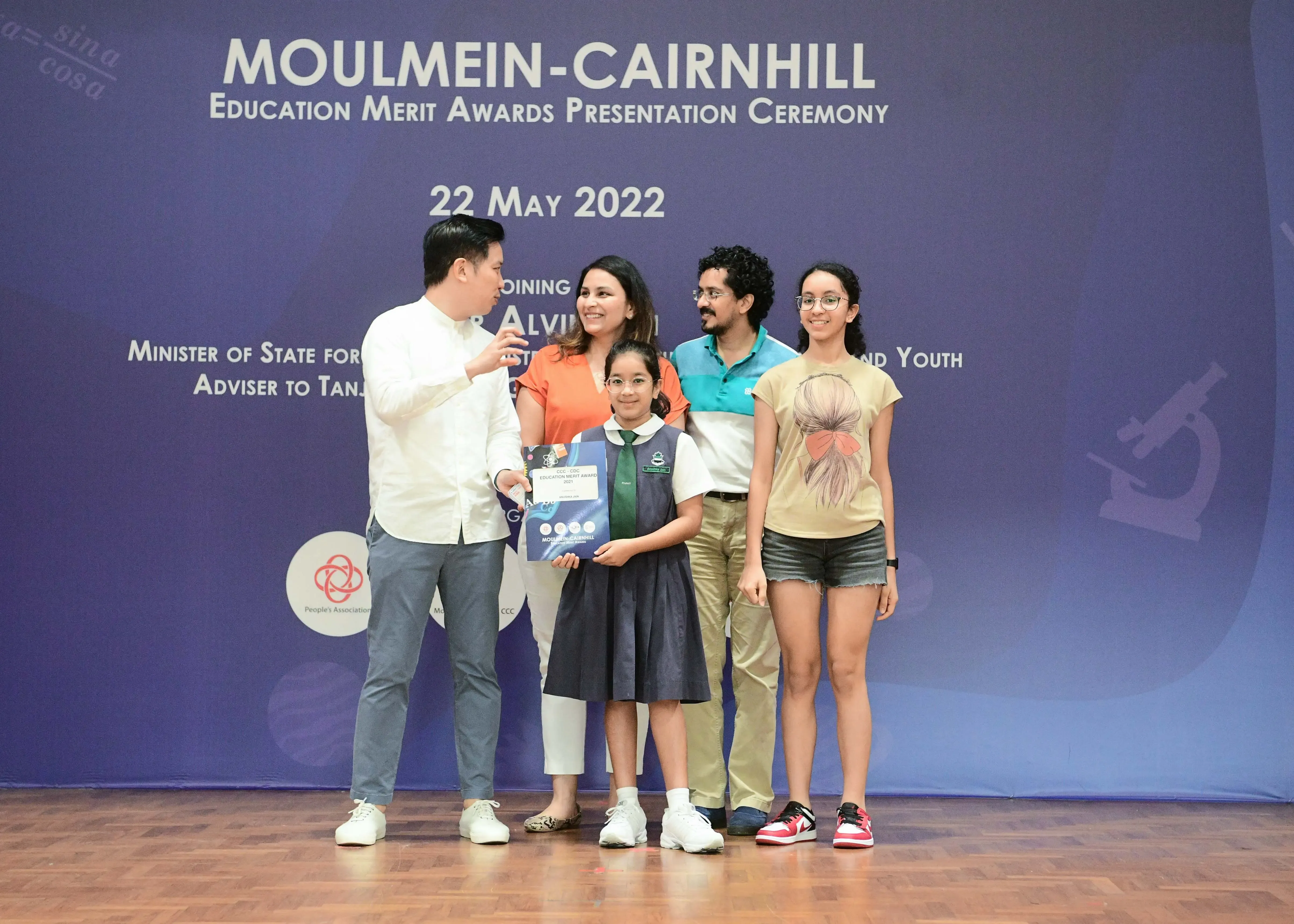 Five people pose on stage at the Moulmein-Cairnhill Education Merit Awards Ceremony on 22 May 2022.