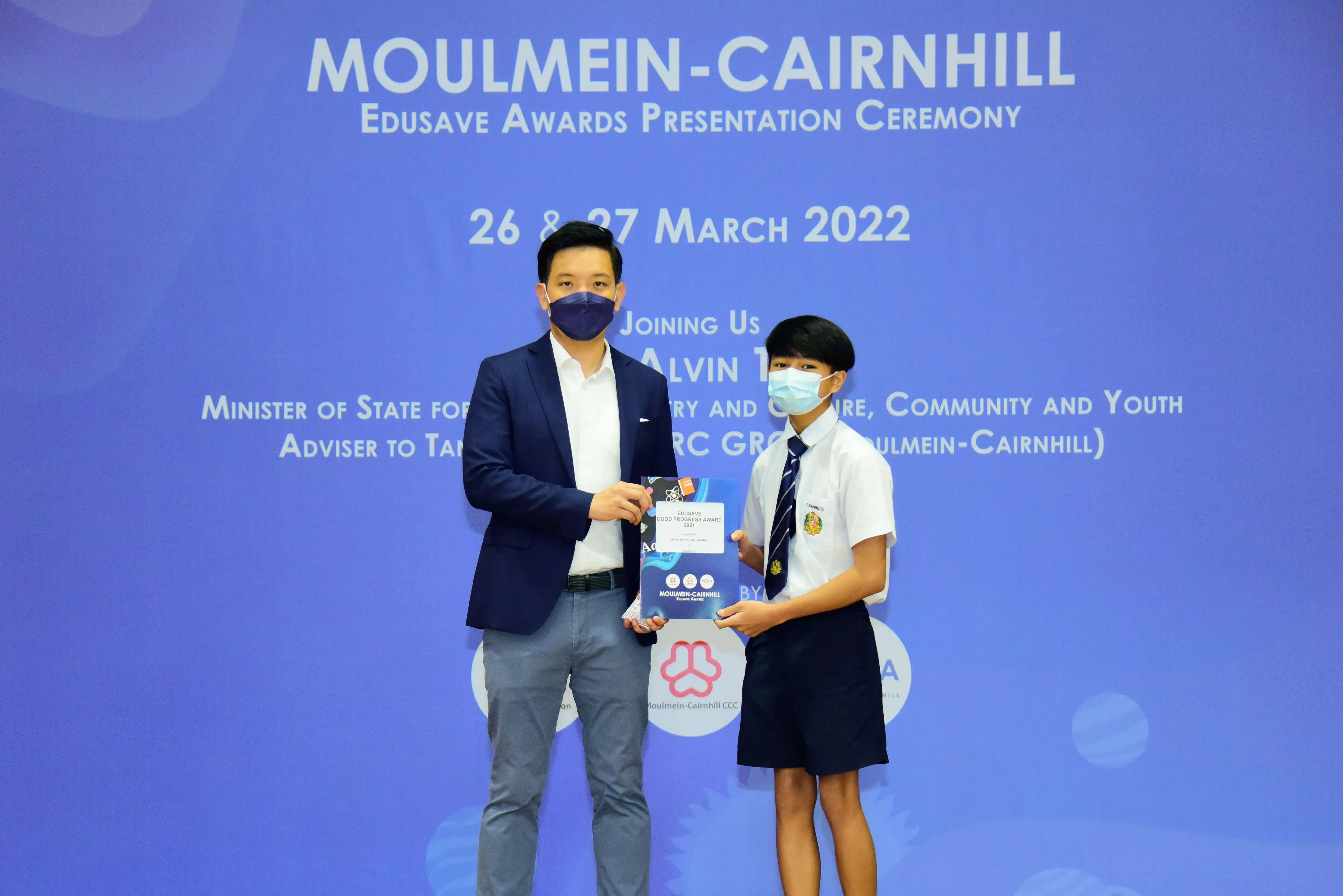 Two masked individuals hold an award certificate at the Moulmein-Cairnhill Edusave Awards Ceremony on March 26-27, 2022.